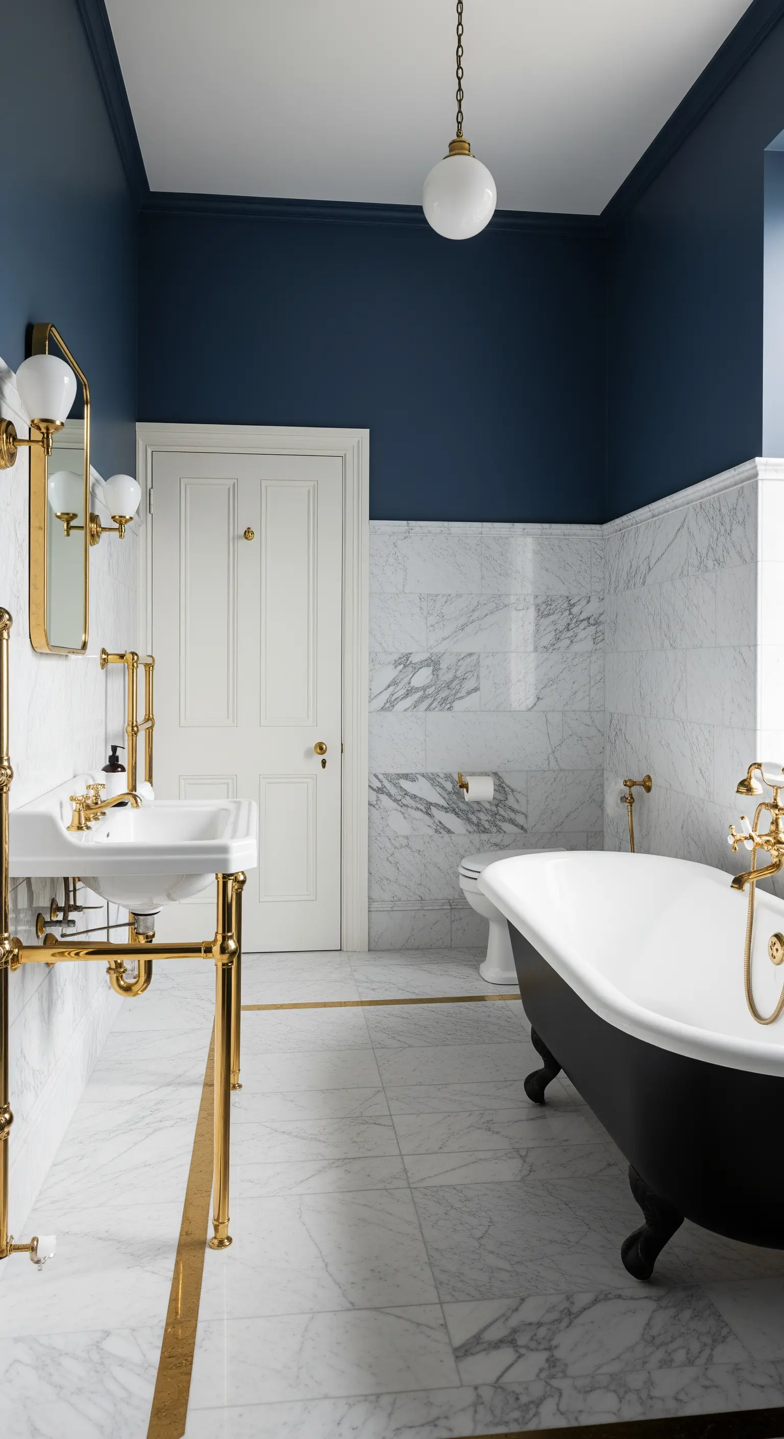 Bagno con pareti bicolore, blu notte e marmo bianco, e vasca freestanding nera con piedini.