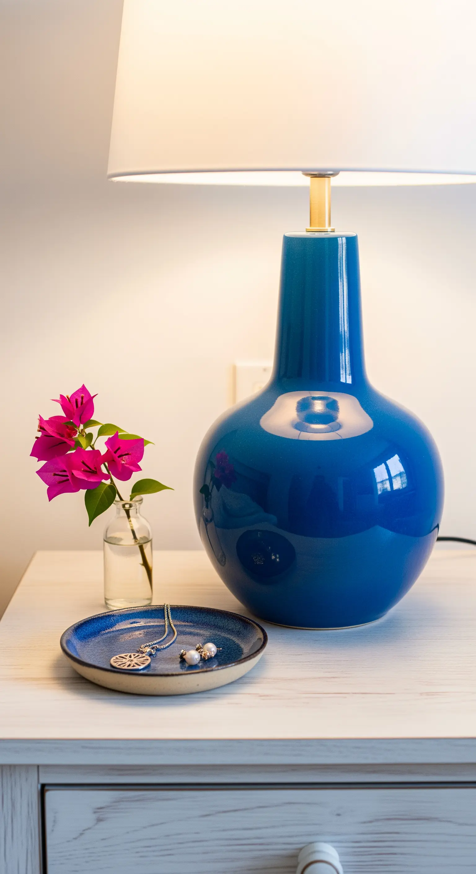 Lampada da comodino con base in ceramica blu lucida e un piccolo vassoio coordinato.