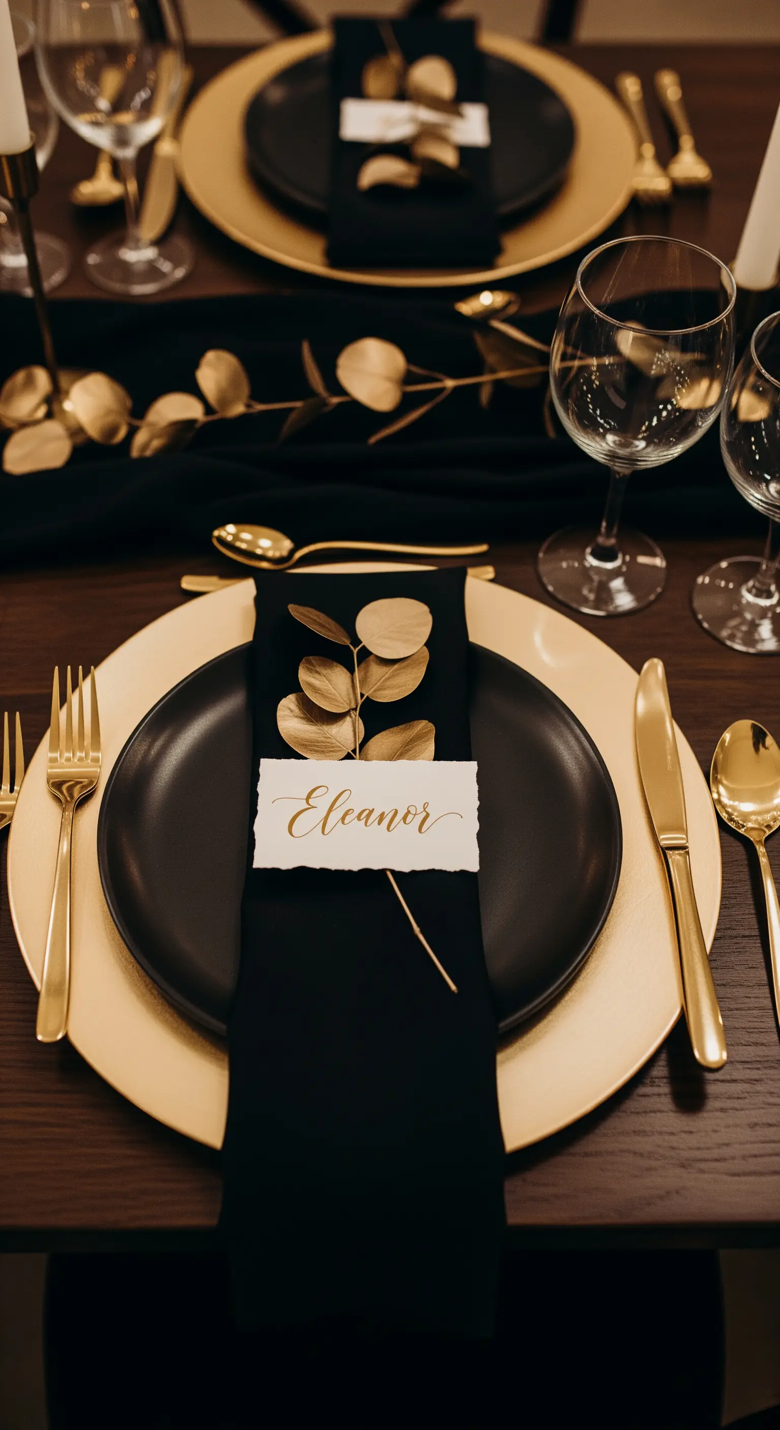 Segnaposto con nome calligrafato su un tovagliolo nero, decorato con un rametto dorato.