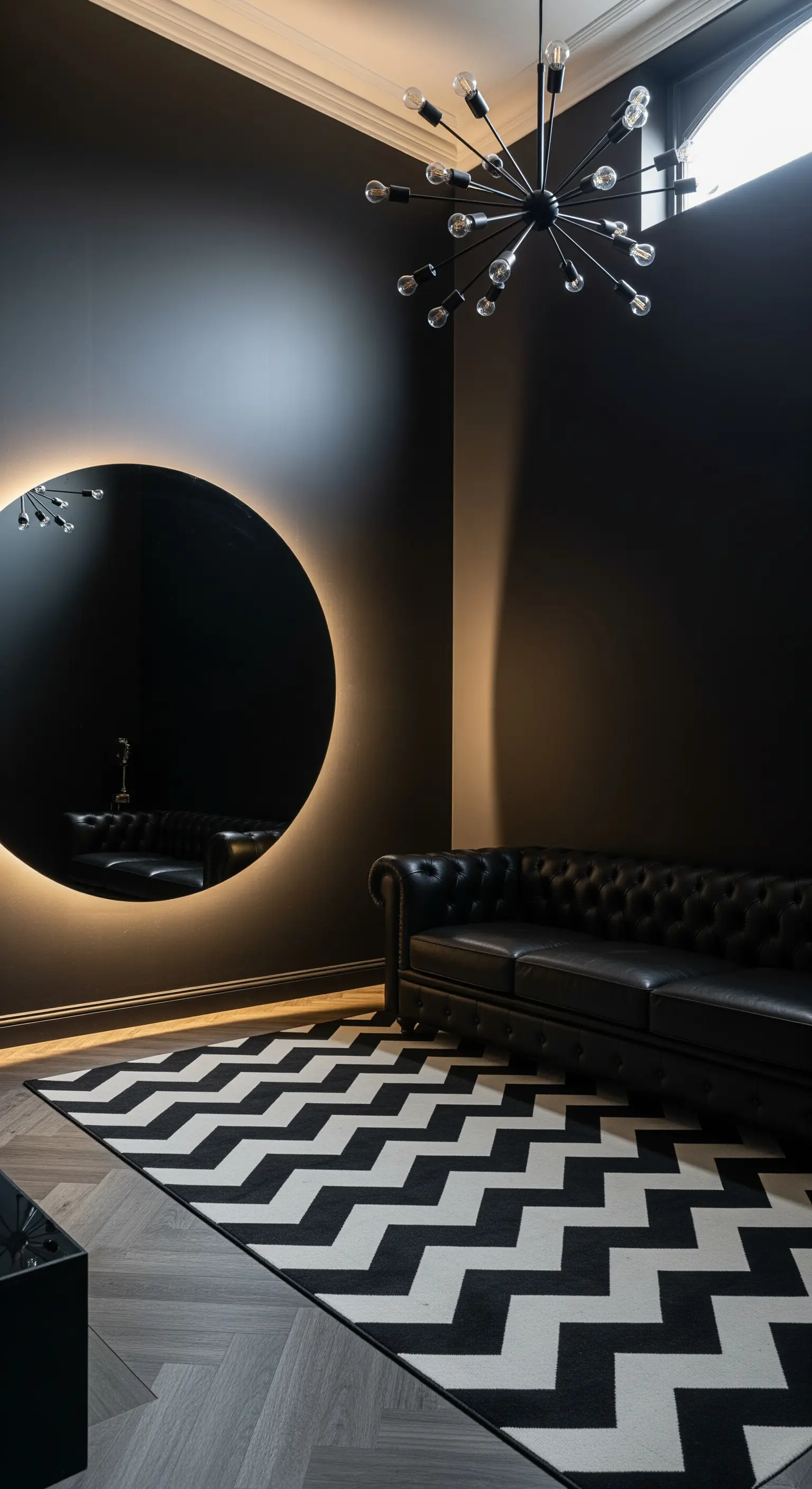 Parete nera con specchio rotondo retroilluminato e tappeto chevron in bianco e nero.