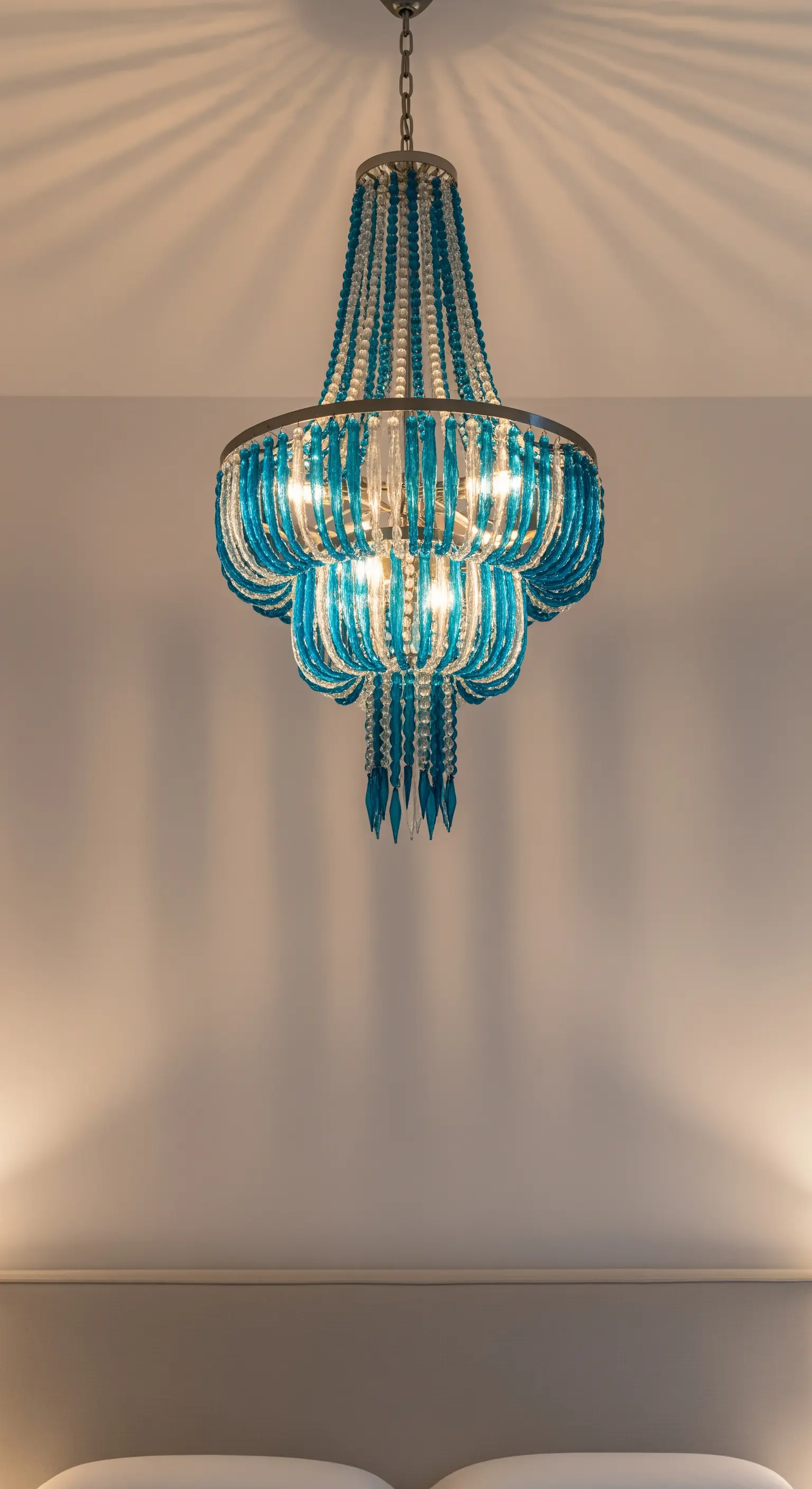 Grande lampadario a sospensione con perline di vetro blu e trasparenti, acceso.