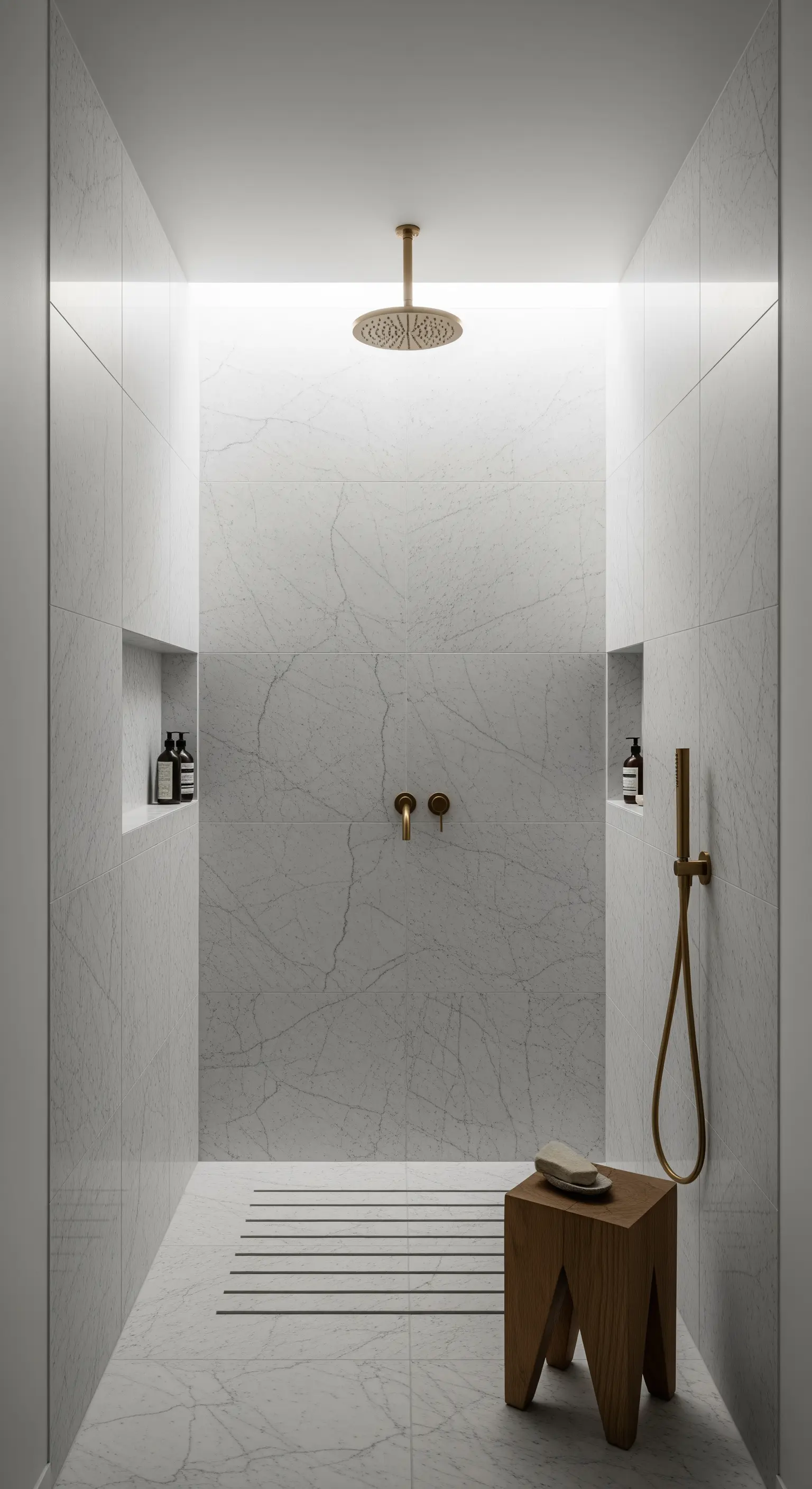 Doccia walk-in minimalista in marmo bianco con rubinetteria in ottone e illuminazione integrata.