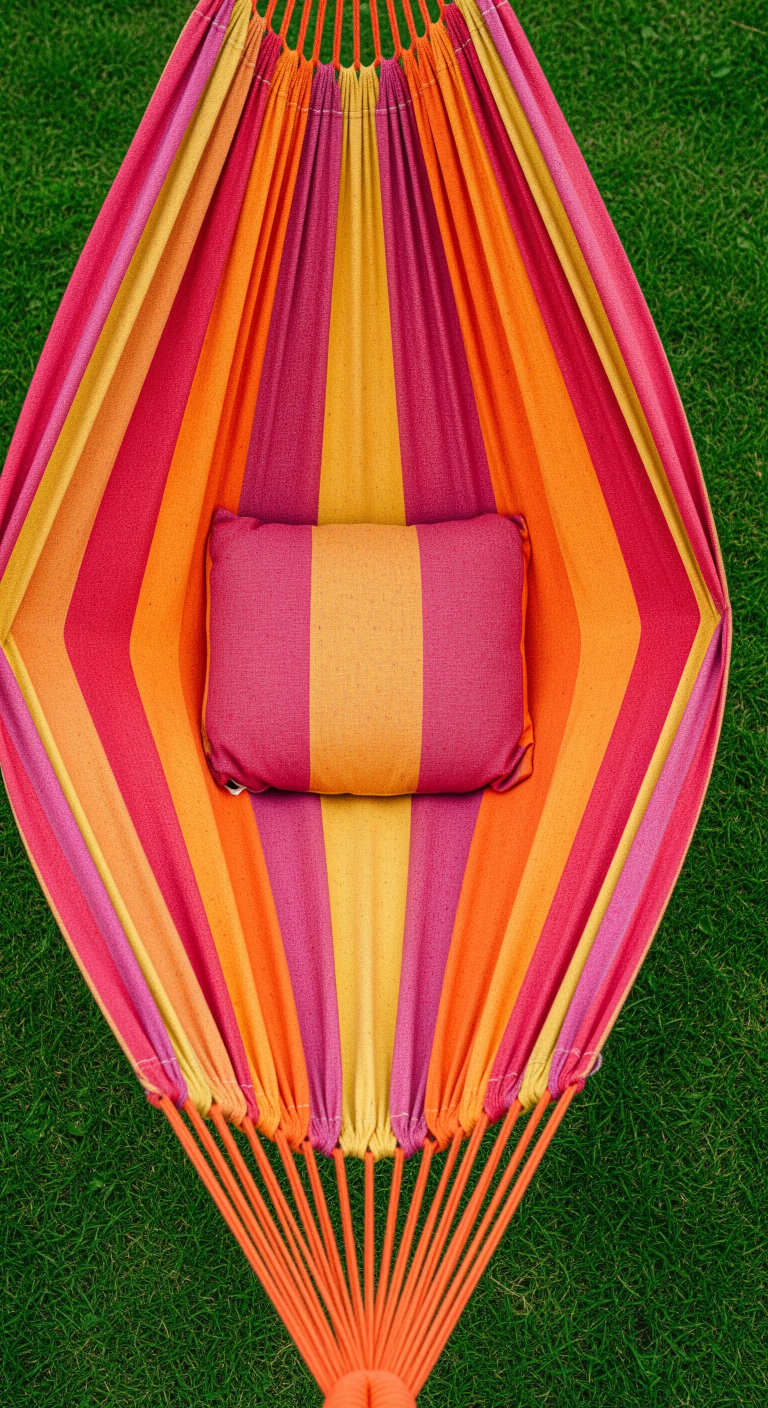 Vista dall'alto di un'amaca con un vivace motivo a righe rosa, arancioni e gialle.