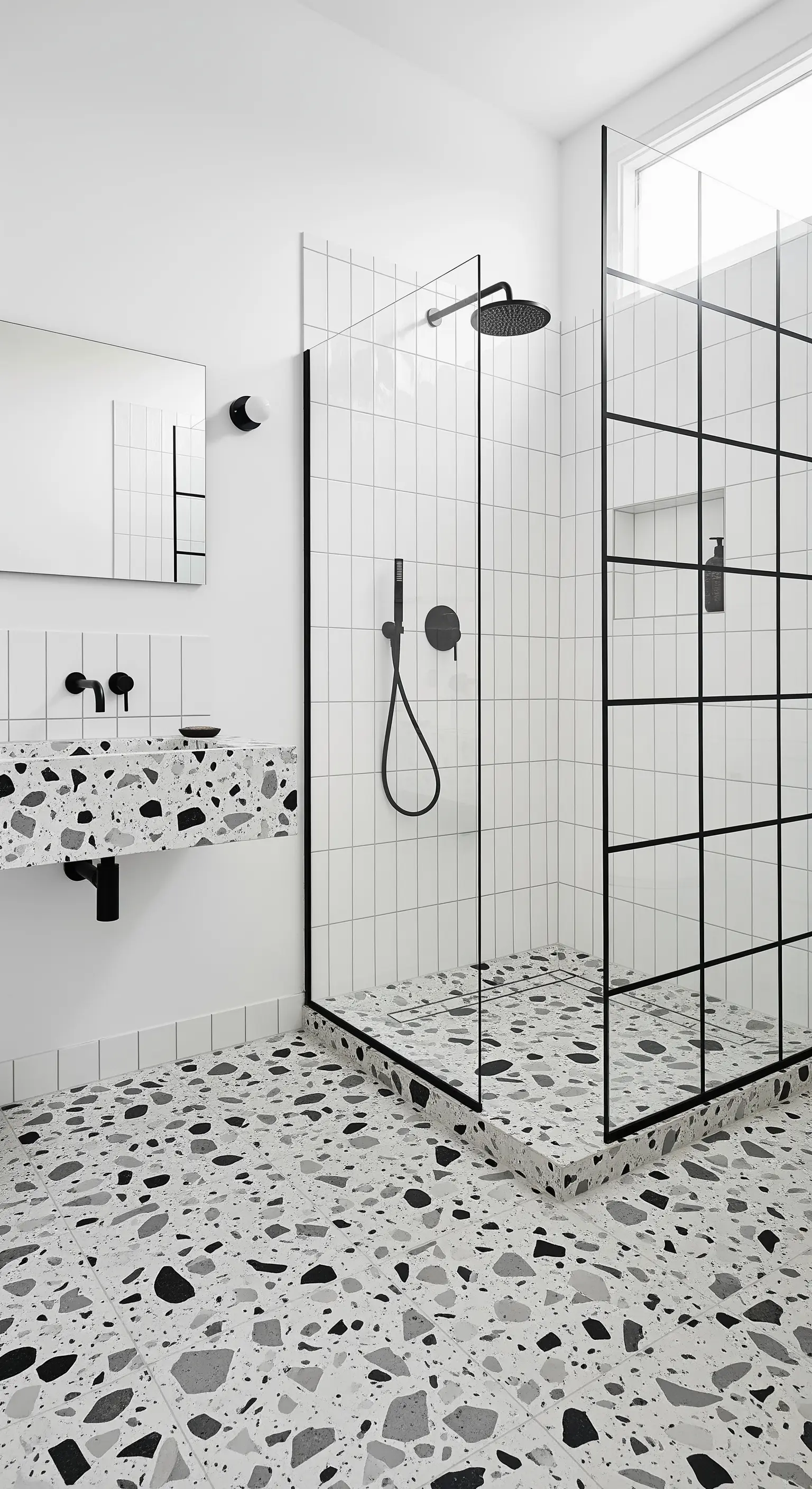 Bagno con pavimento e lavabo in terrazzo e box doccia con griglia nera.