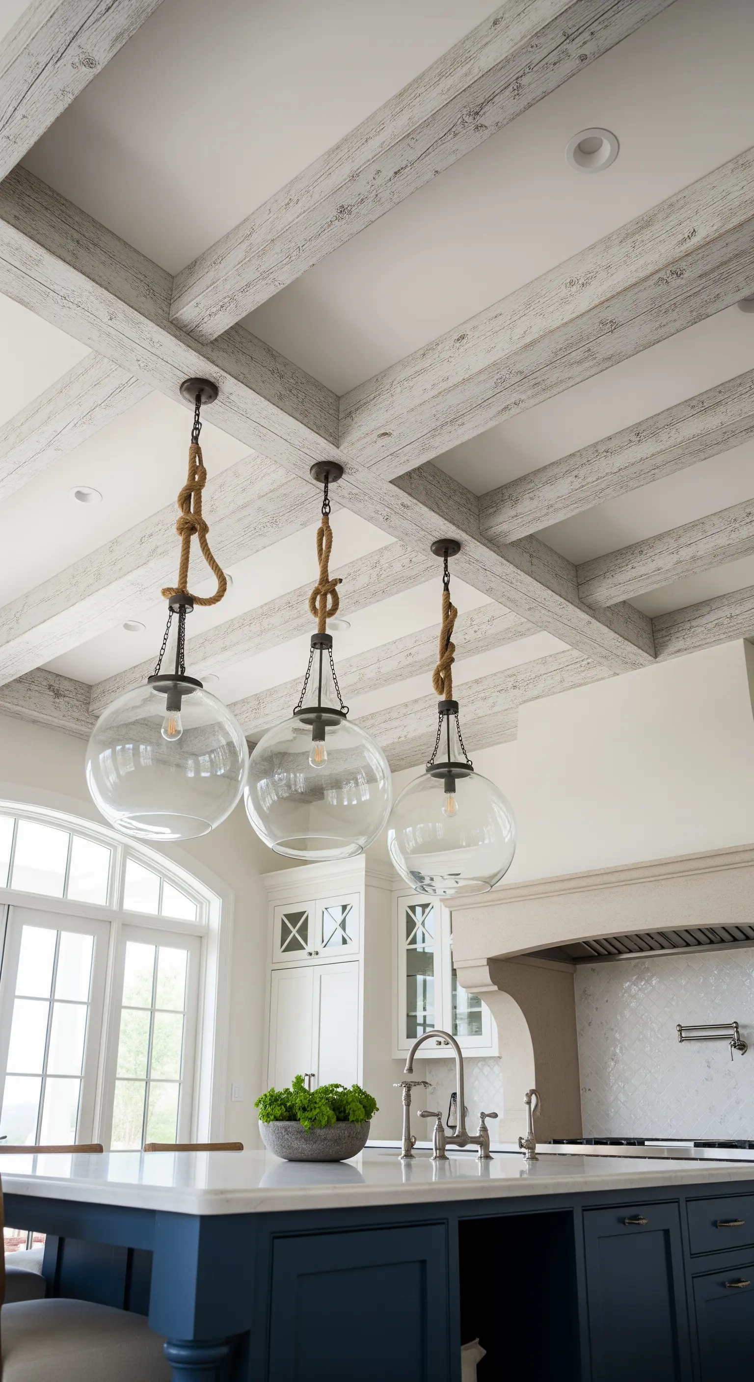 Lampade a sospensione in vetro con corde nautiche sopra un'isola blu navy.