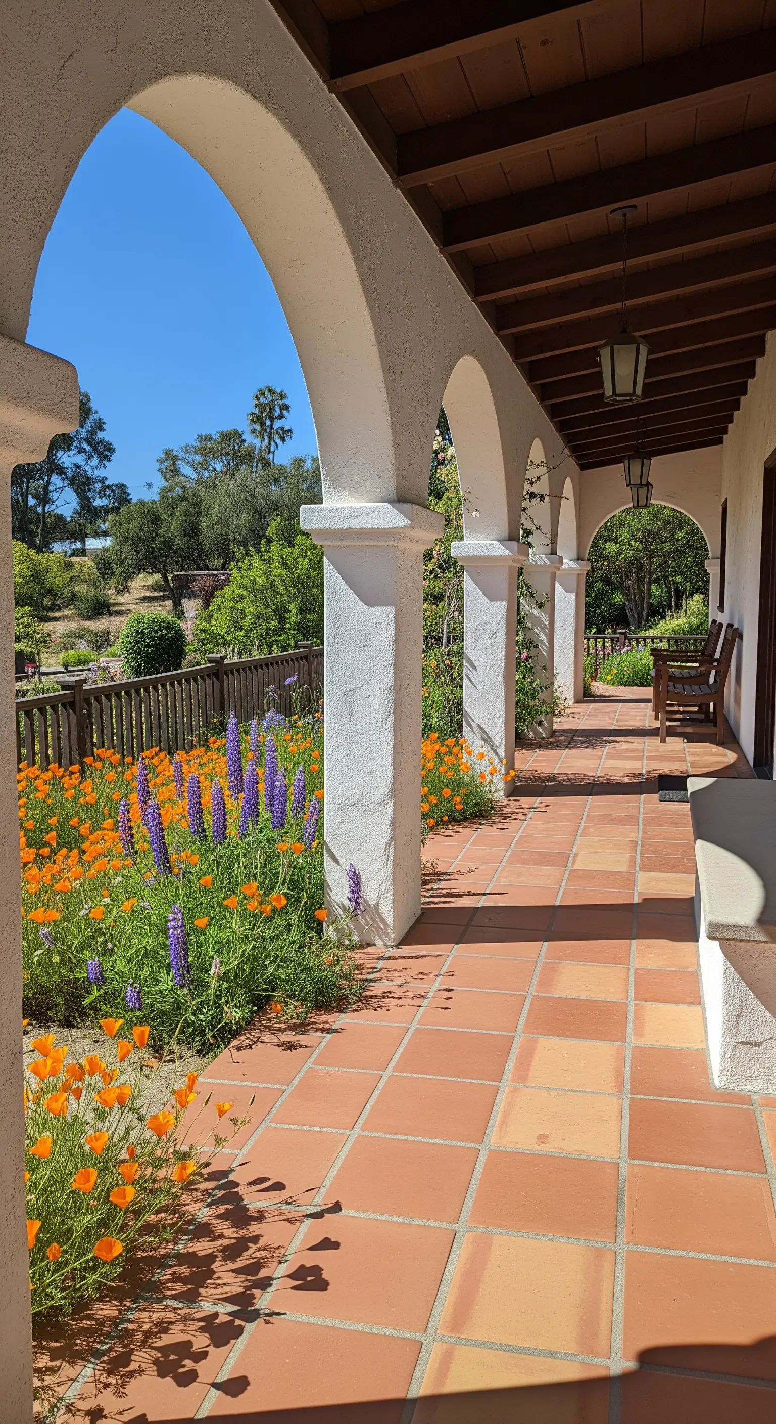 Portico in stile coloniale con archi bianchi che incorniciano un giardino di papaveri arancioni.