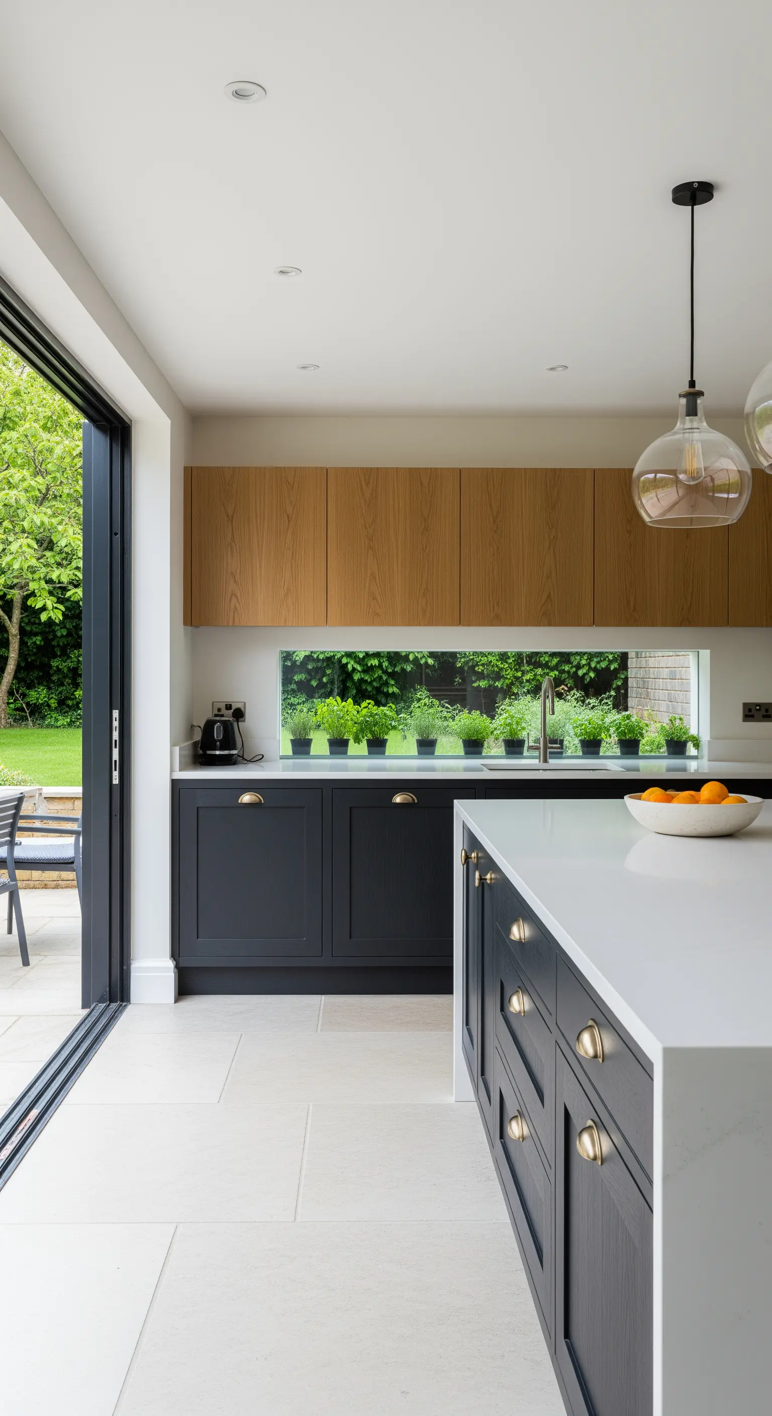 Cucina con basi scure, pensili chiari e una finestra orizzontale come paraschizzi.