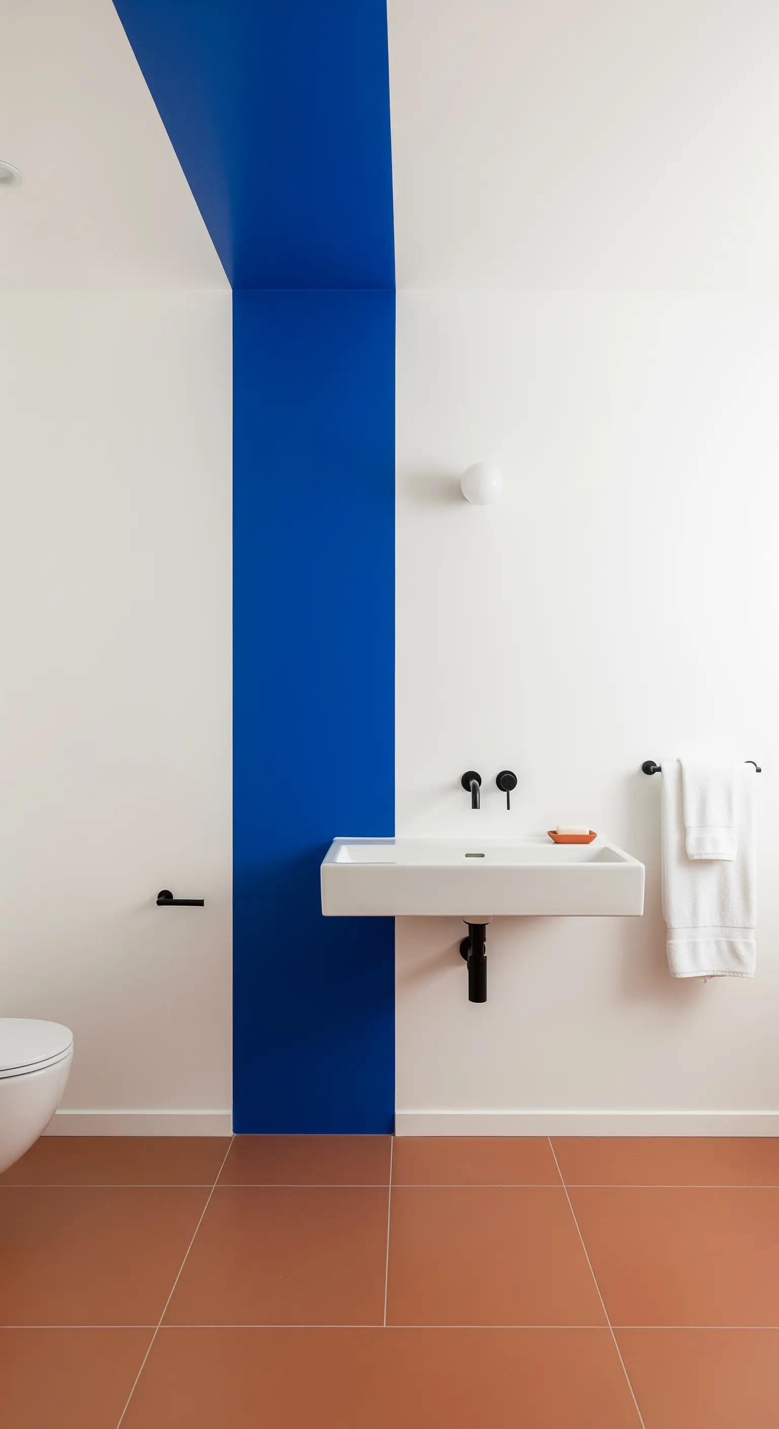 Bagno minimalista con una striscia verticale blu intenso dietro al lavabo a parete.
