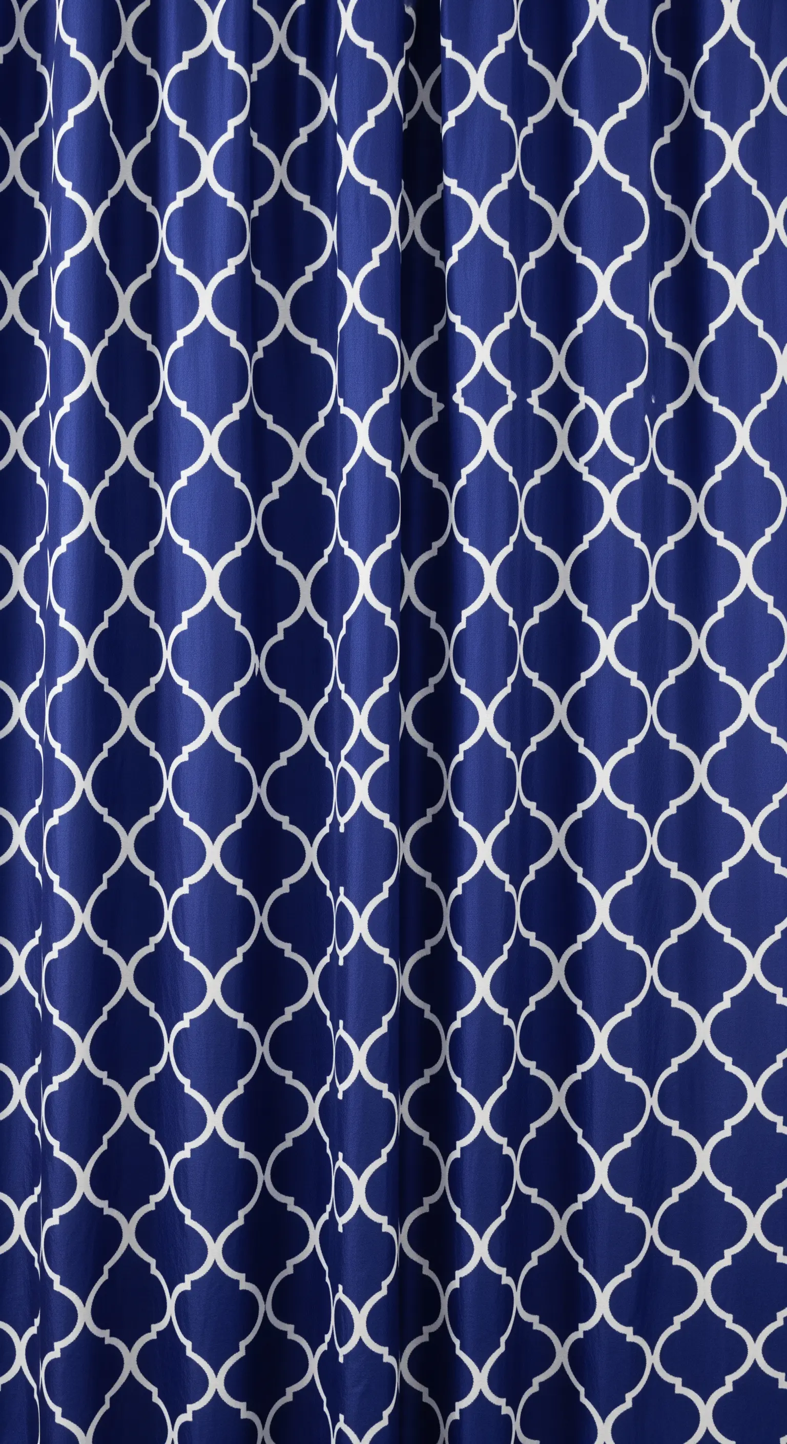 Dettaglio di una tenda blu con un motivo a traliccio marocchino bianco, netto e geometrico.
