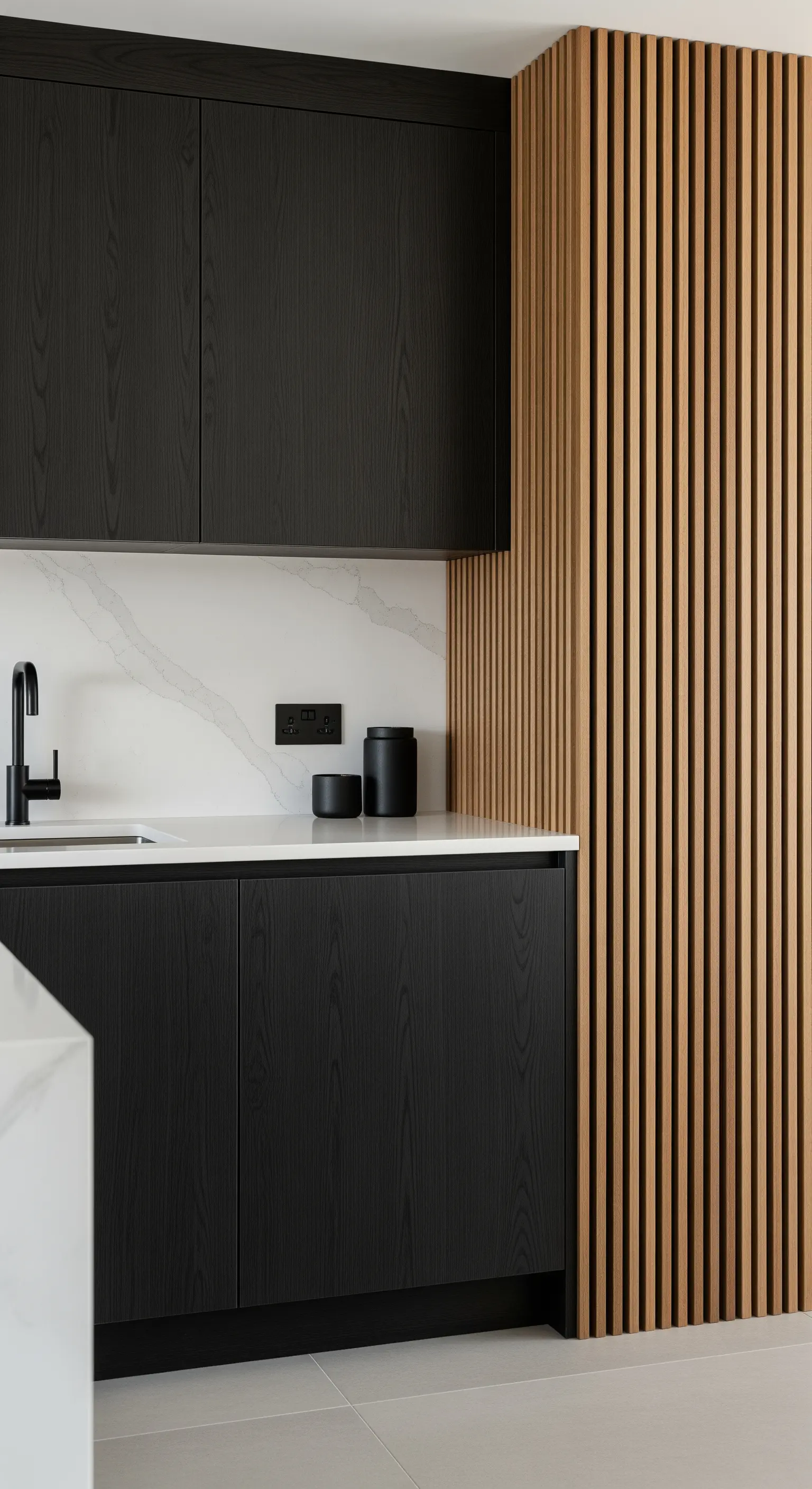 Dettaglio di una cucina nera con un pannello decorativo in legno a listelli verticali.