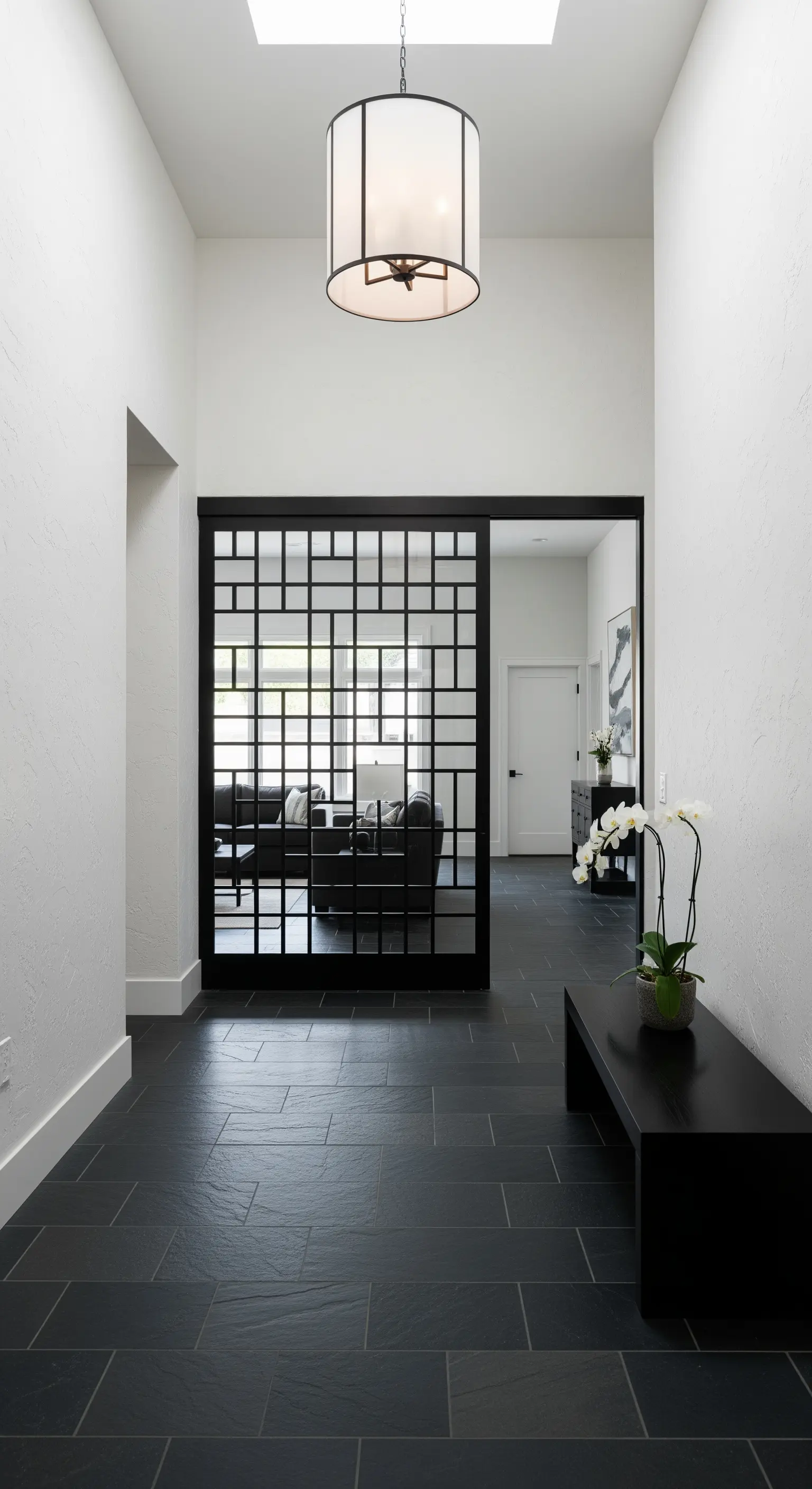 Corridoio minimalista con pavimento in ardesia e una porta scorrevole a griglia nera in stile shoji.