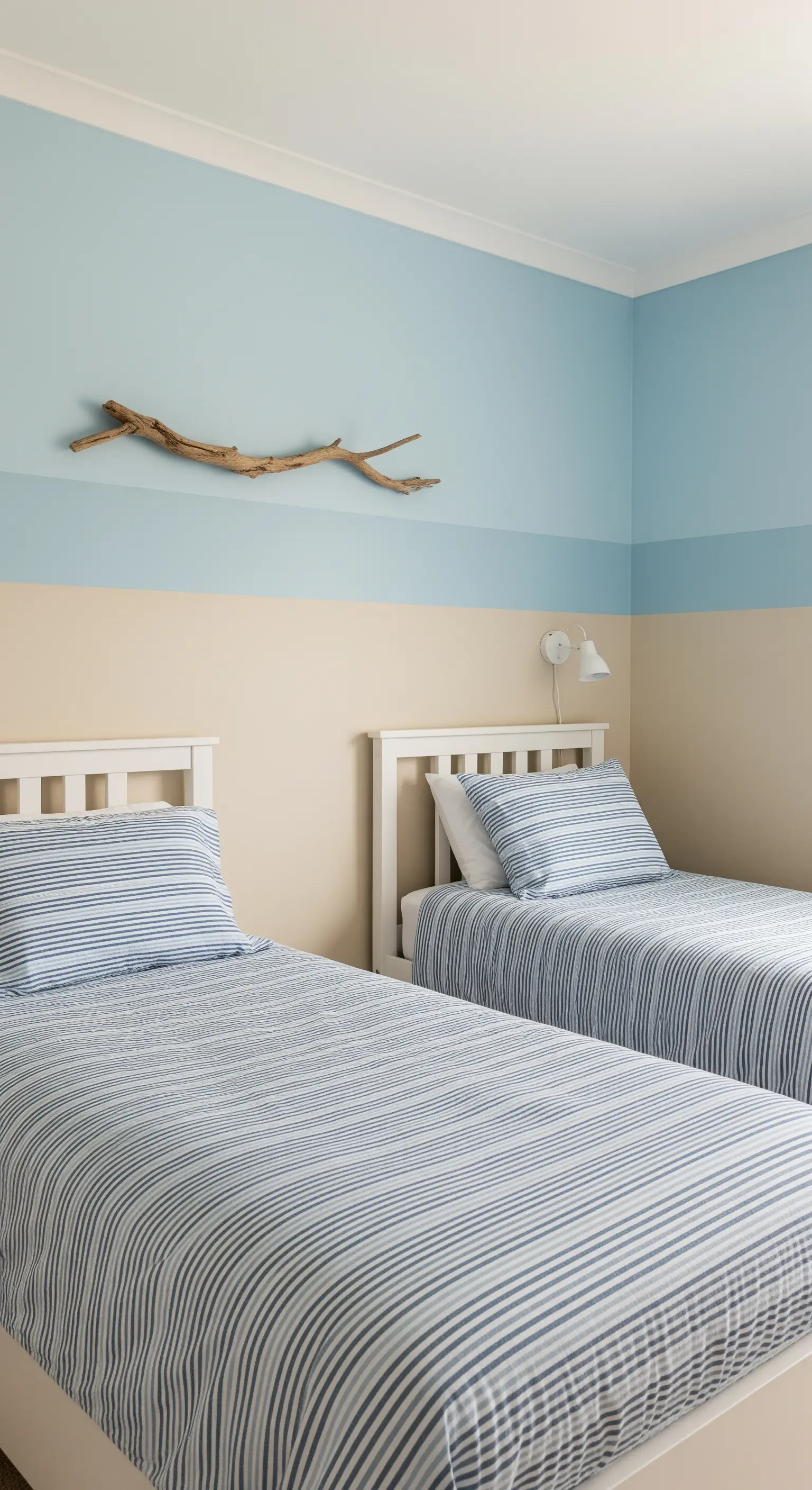 Camera per ragazzi con pareti bicolore sabbia e azzurro, e letti bianchi con lenzuola a righe.