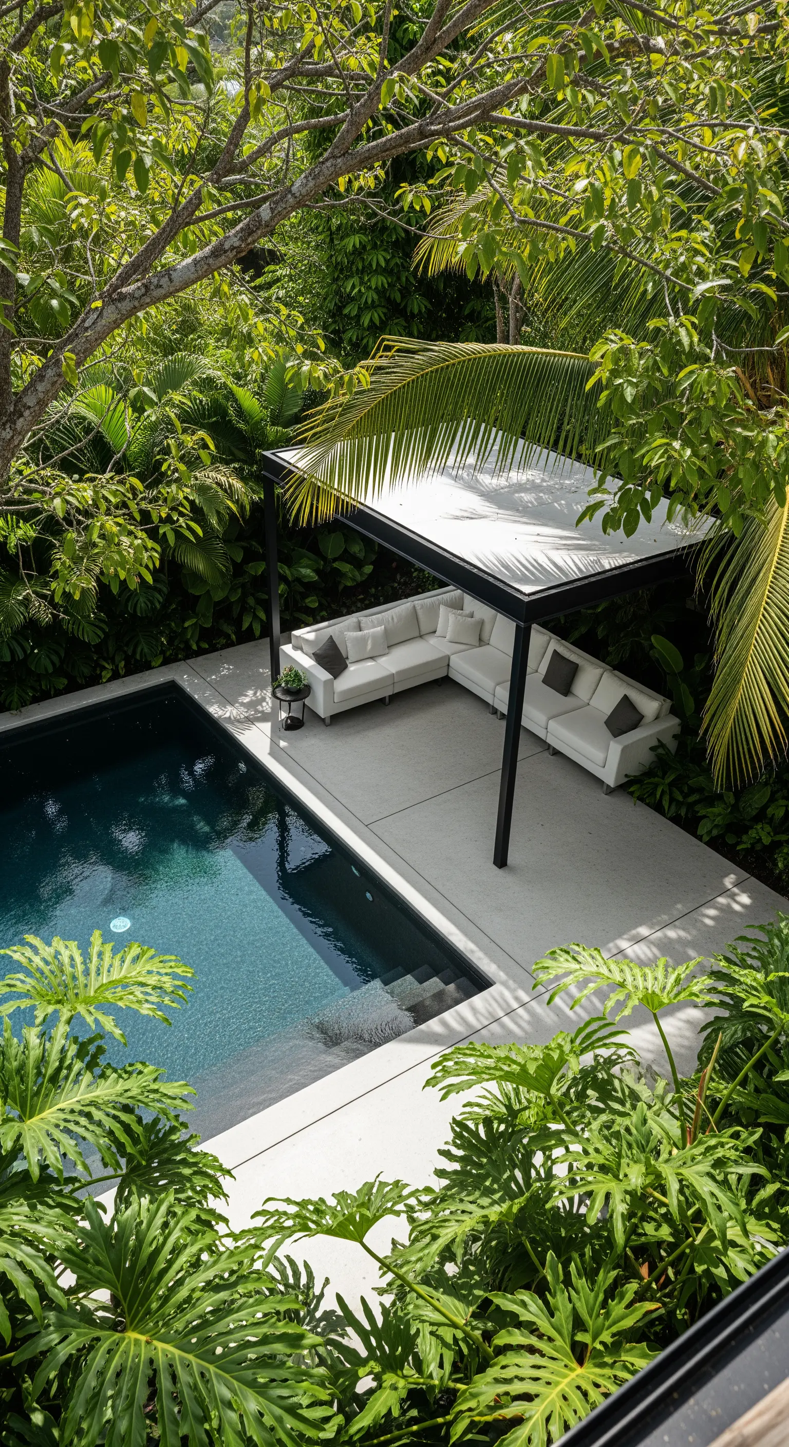 Lounge bianco sotto un pergolato nero, circondato da una vegetazione lussureggiante