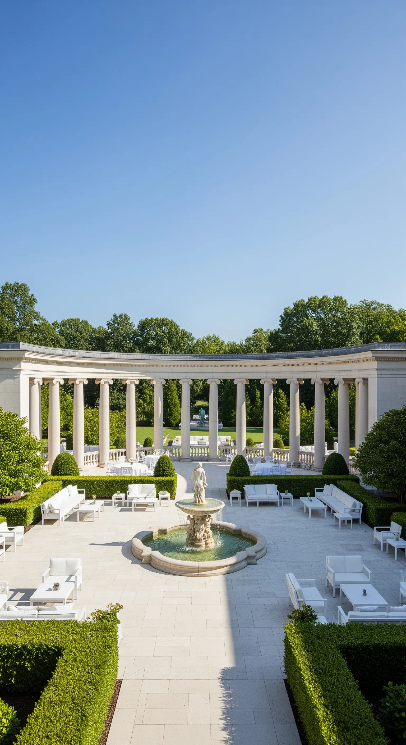 Ampio patio a semicerchio con colonnato, arredi bianchi e una fontana centrale per eventi.