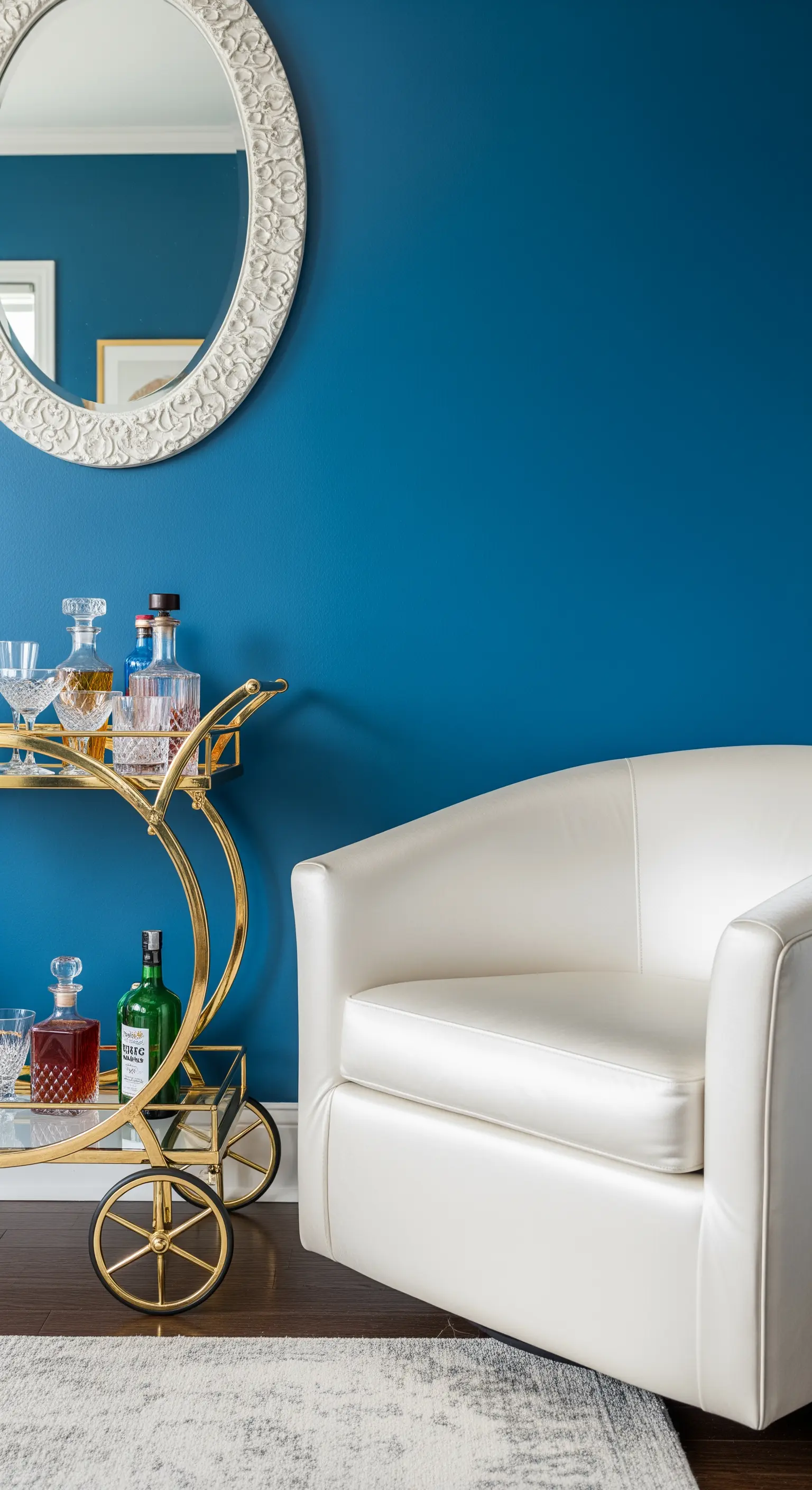 Poltrona bianca e carrello bar dorato su una parete blu brillante.