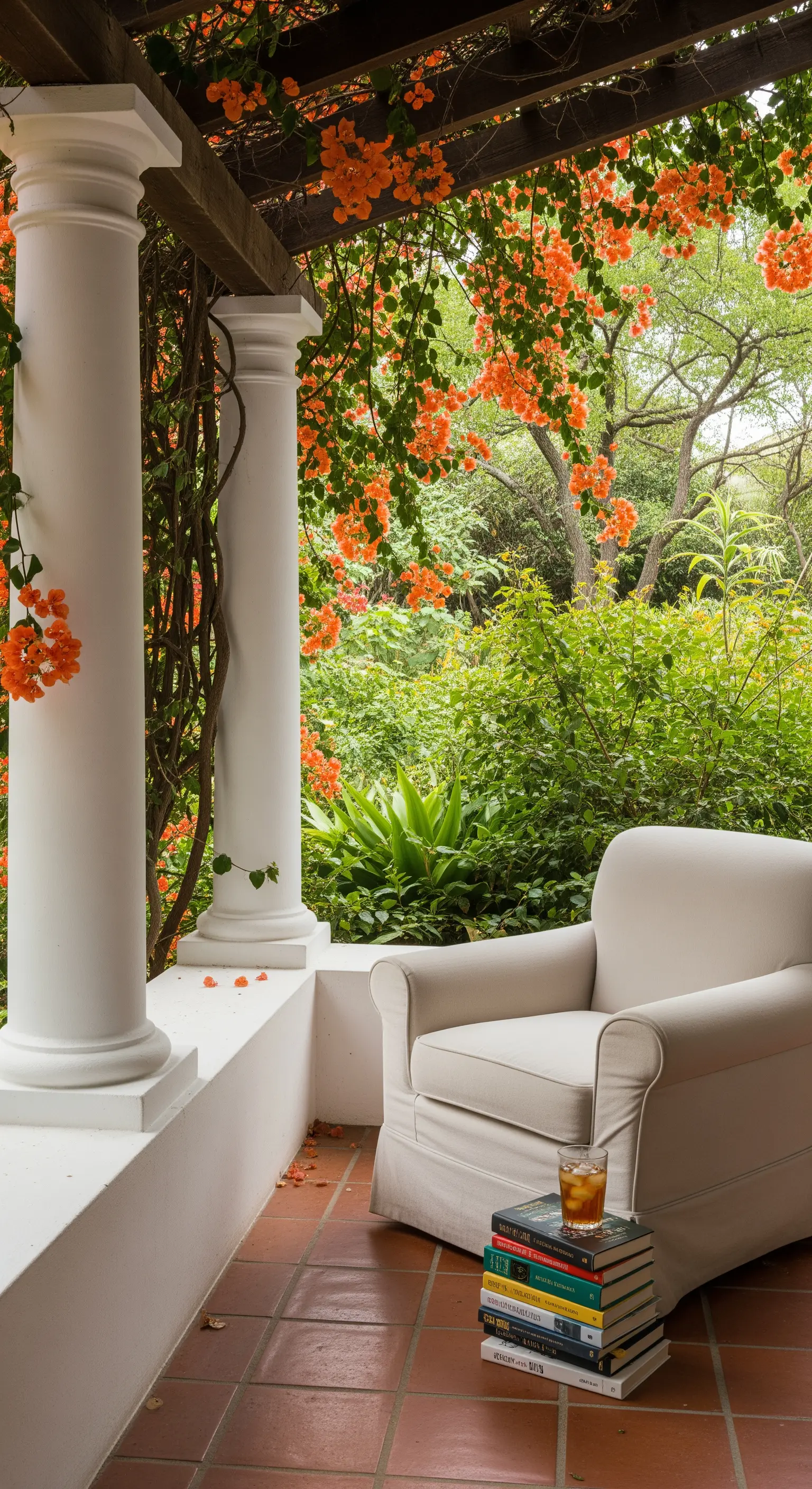 Angolo lettura su un portico con poltrona bianca, libri e bouganville arancione