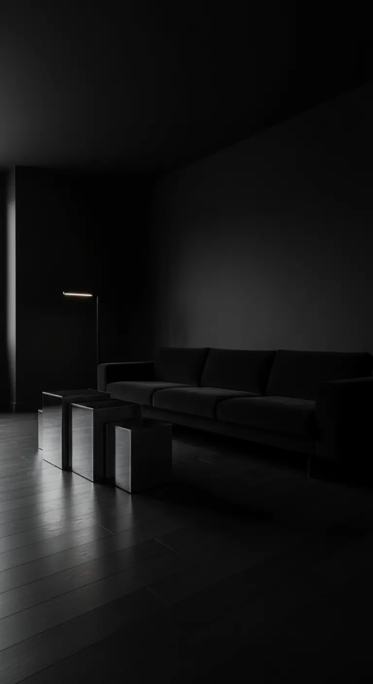Salotto total black con divano scuro, tavolini a specchio e luce d'accento.