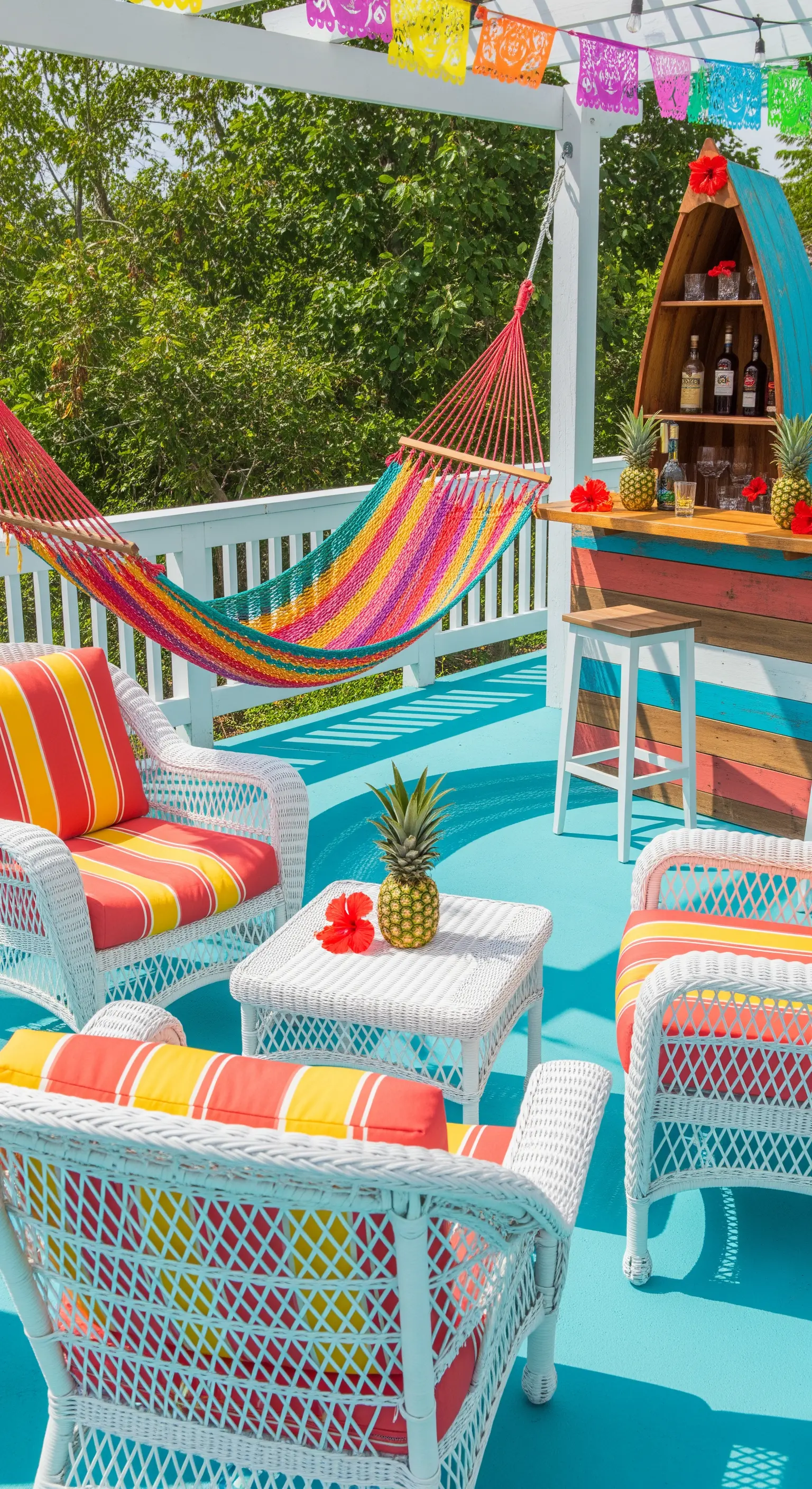 Patio colorato con pavimento azzurro, amaca a righe e bar in legno a forma di barca.