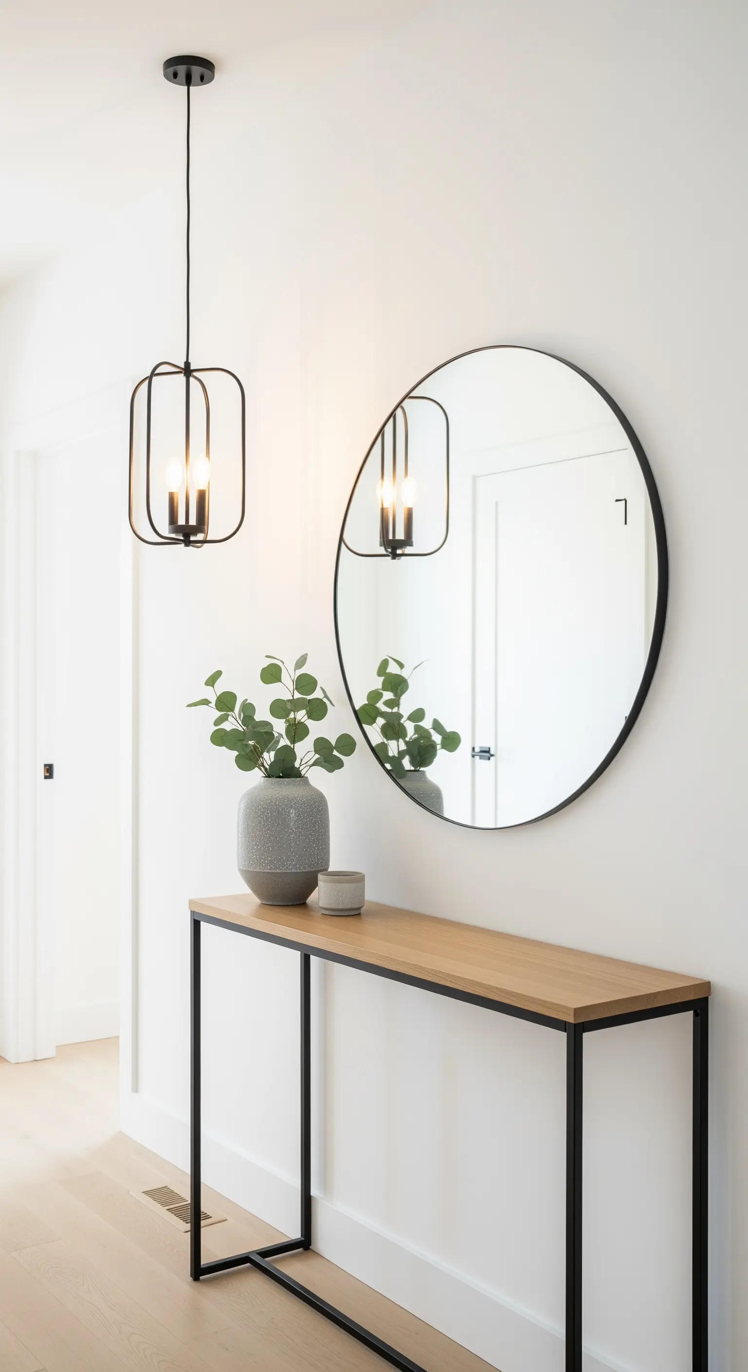 Consolle in rovere e metallo nero con specchio rotondo e lampada a sospensione geometrica.