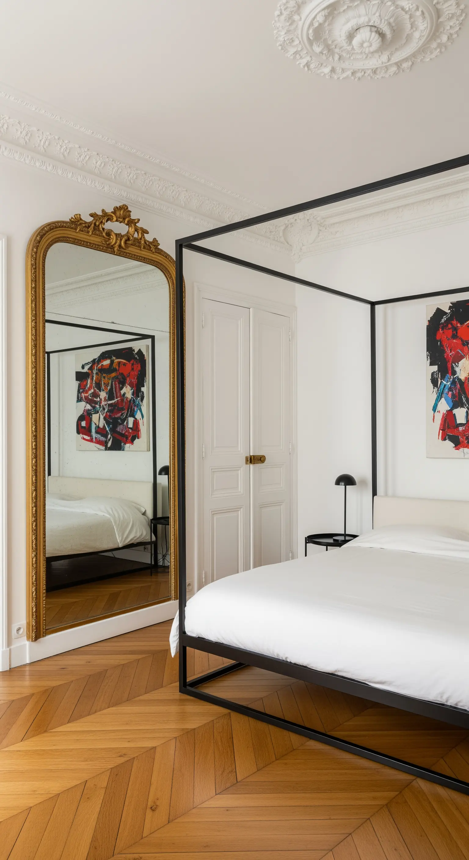 Letto a baldacchino nero e minimalista accostato a un grande specchio con cornice dorata barocca.