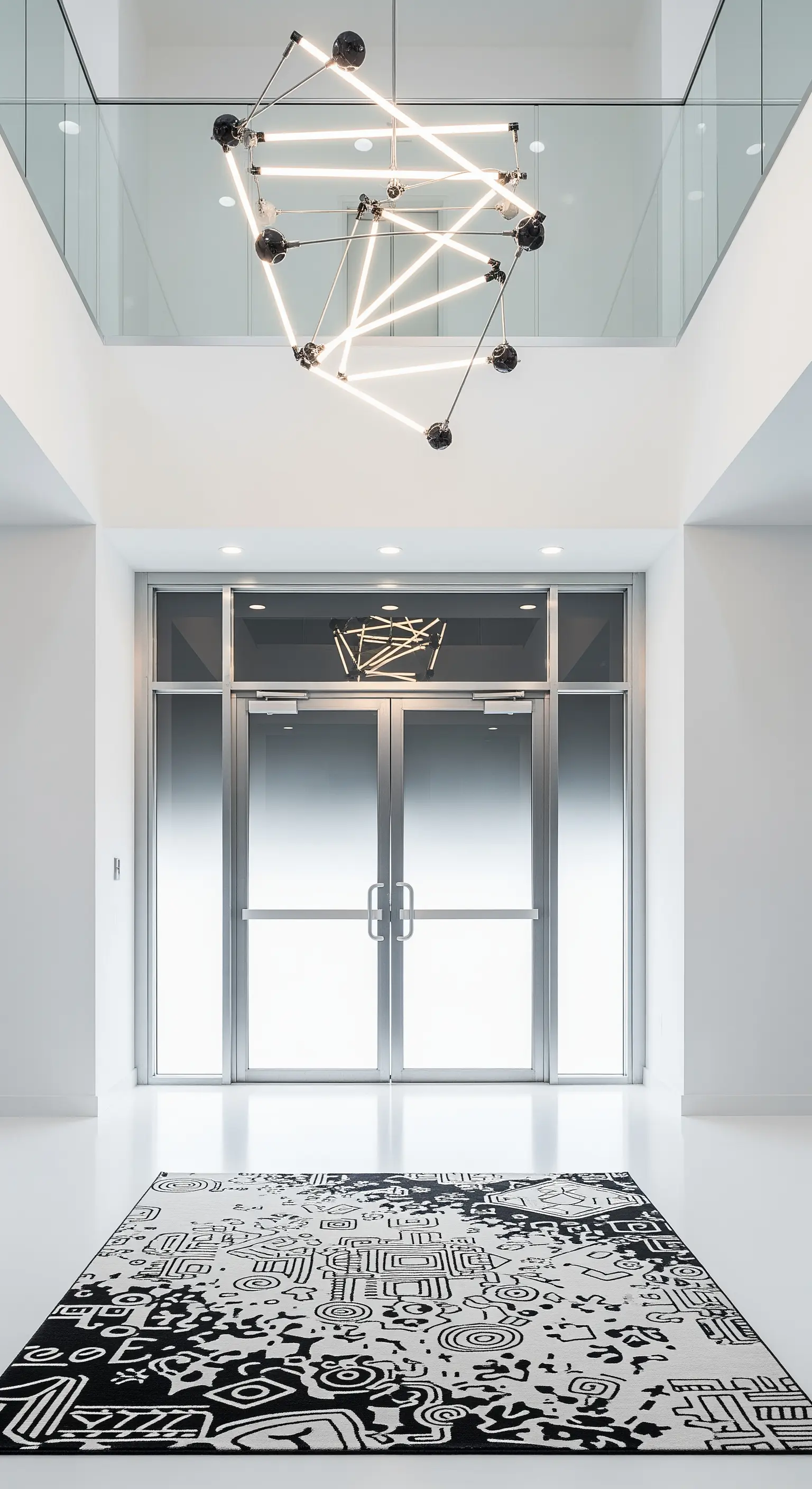 Ingresso minimalista bianco con un'installazione luminosa a LED e un tappeto astratto.