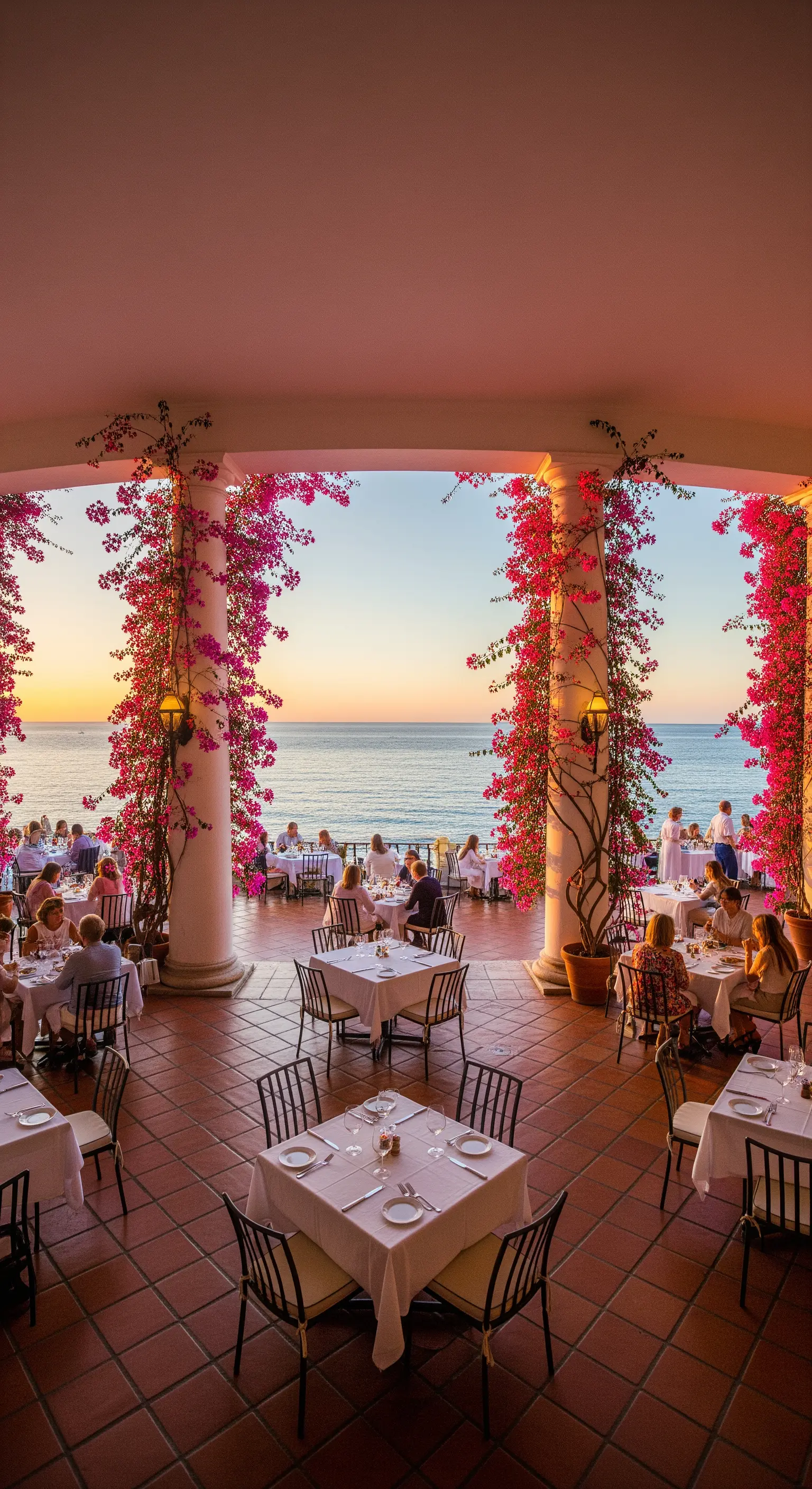 Portico di un ristorante affacciato sul mare al tramonto, con tavoli e bouganville sulle colonne