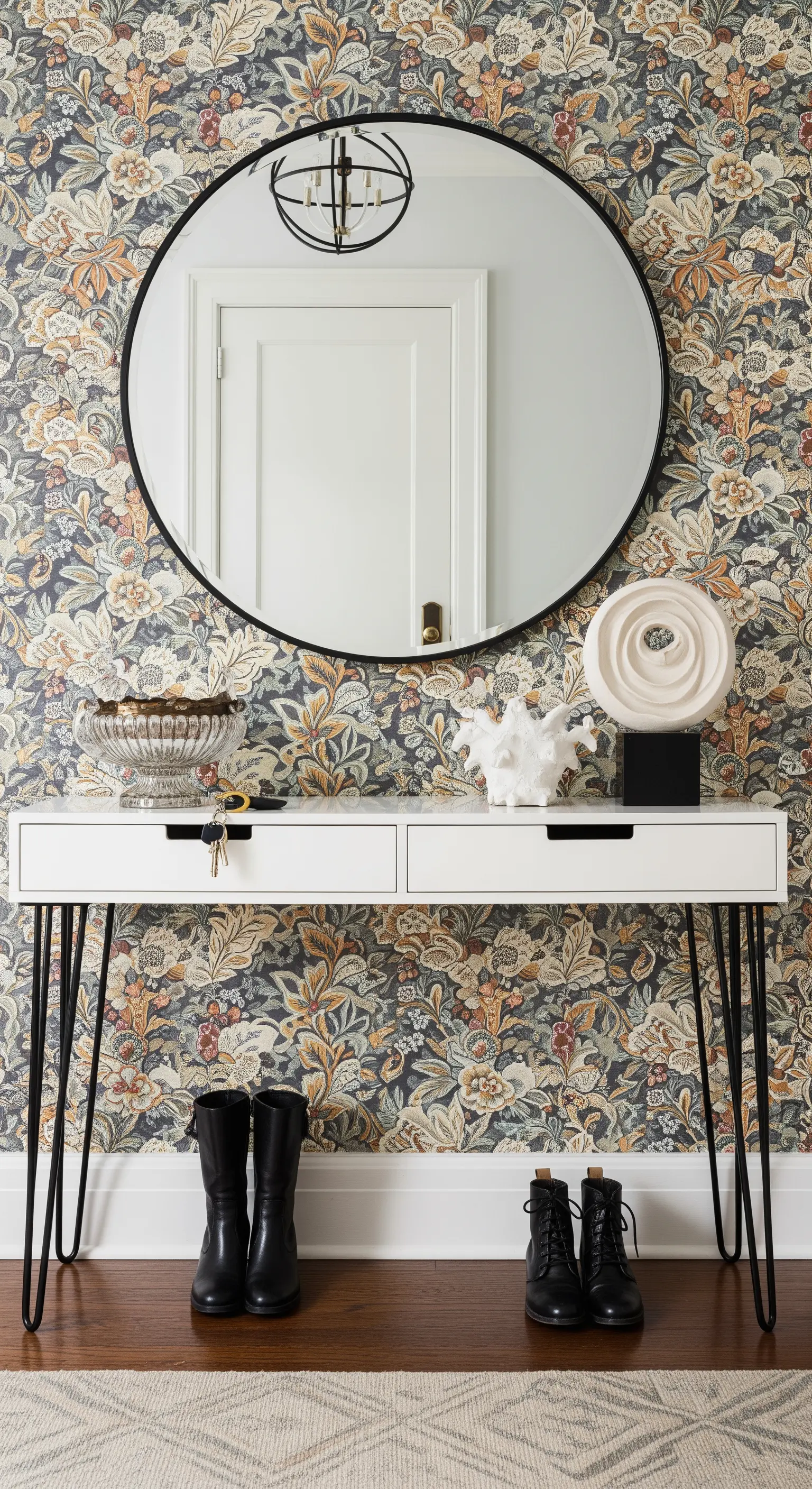 Ingresso con carta da parati floreale, consolle bianca con gambe a spillo e specchio rotondo.