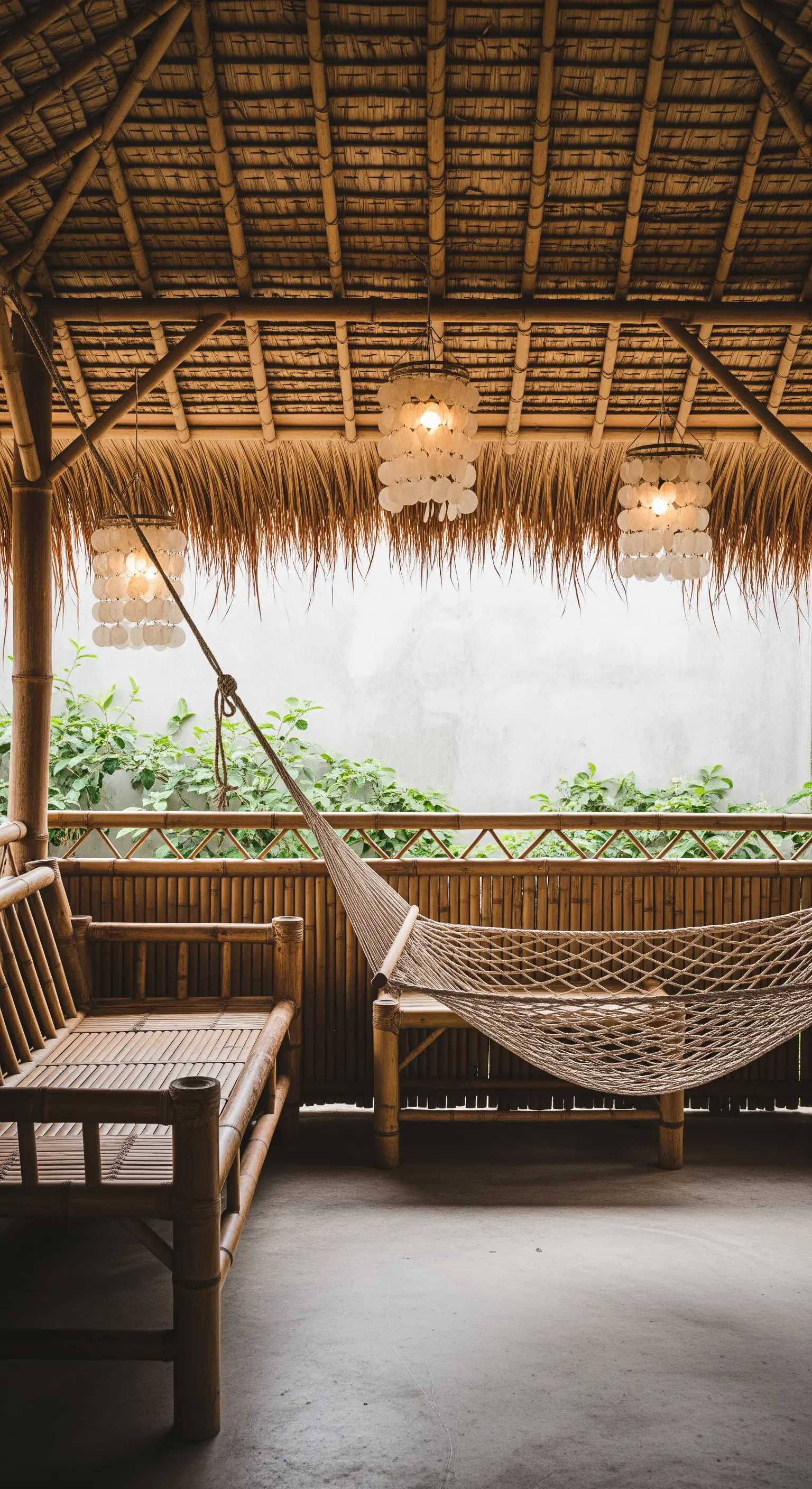 Veranda in bambù con amaca intrecciata e lampadari realizzati con conchiglie di capiz.
