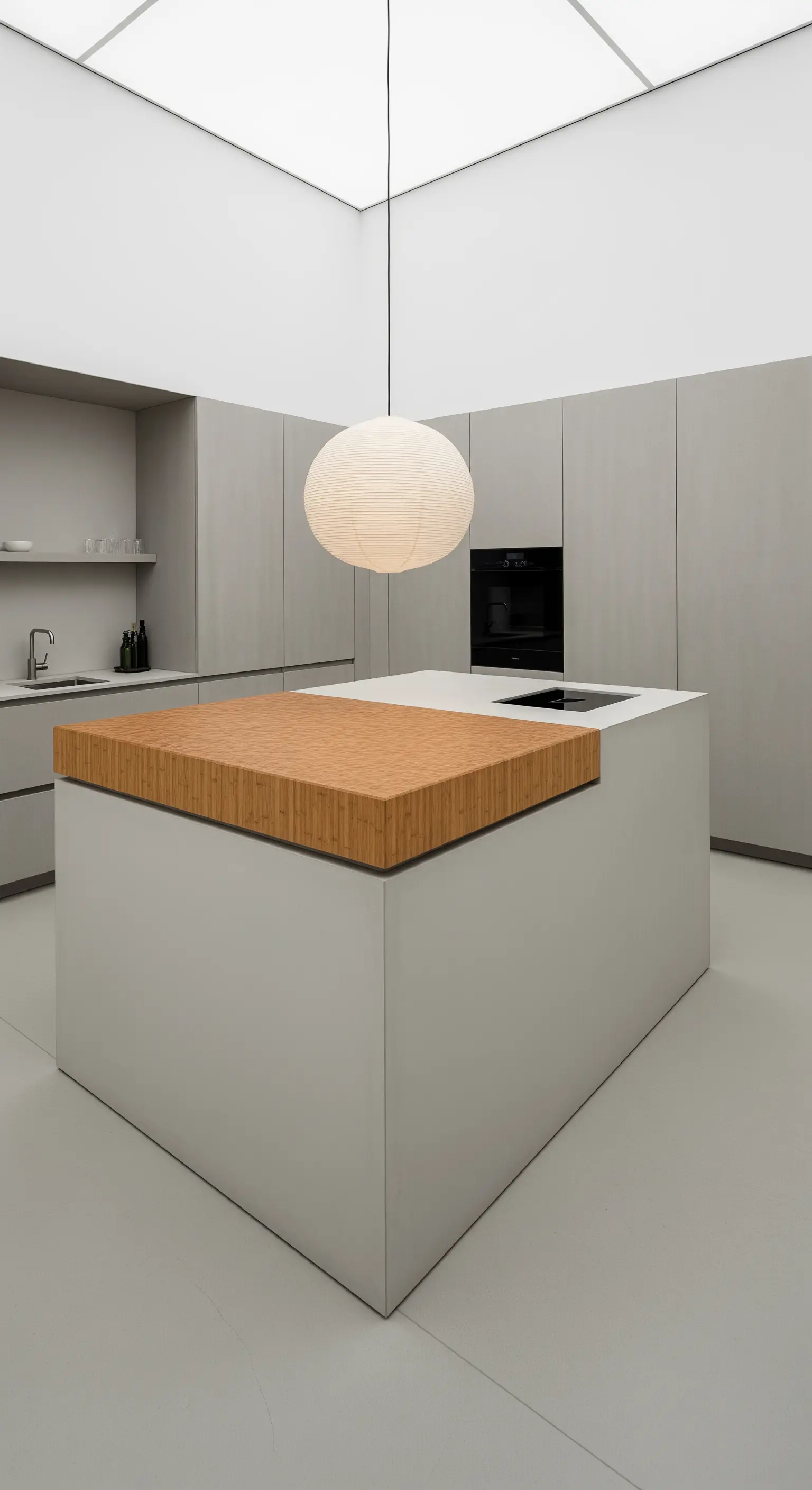 Cucina grigia ultra-minimale con una grande lanterna di carta sferica sopra l'isola.