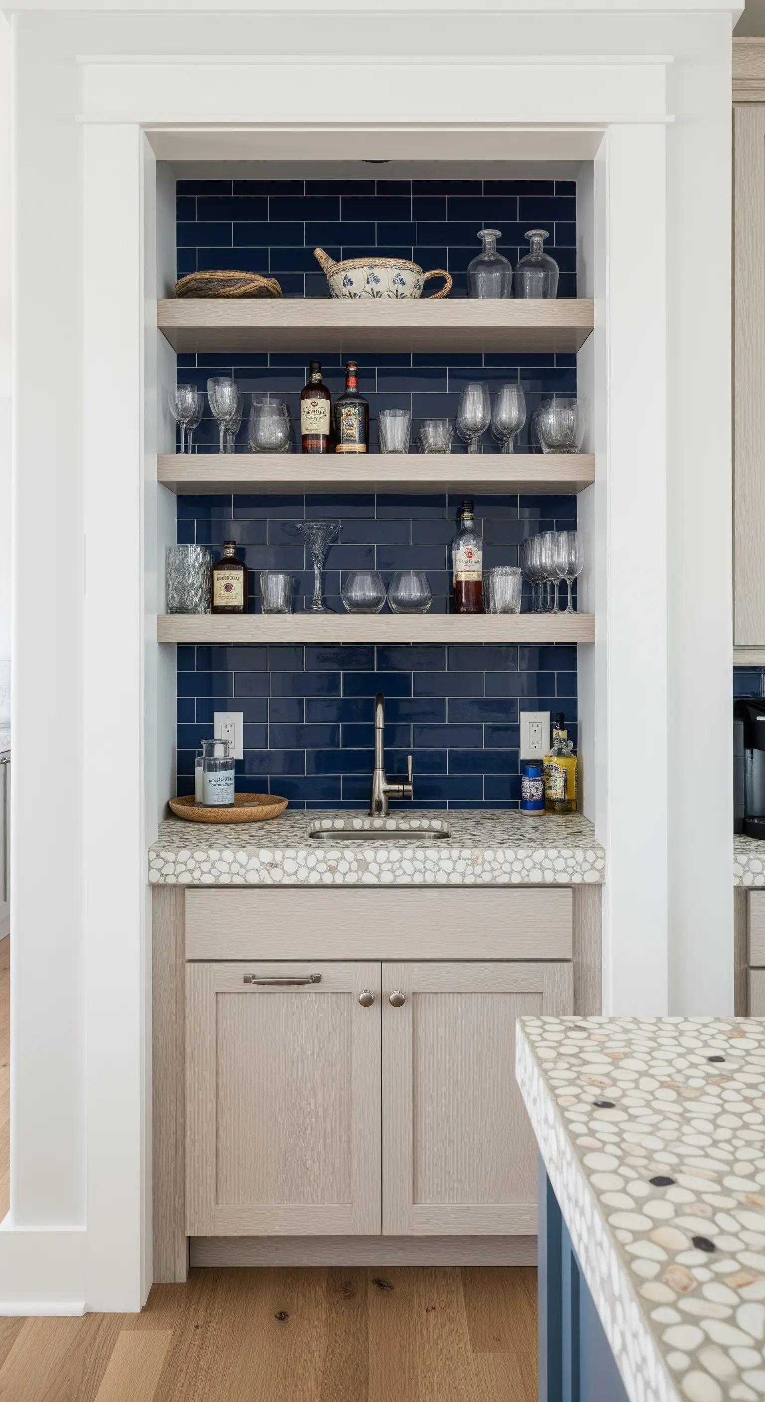 Nicchia bar con piastrelle blu notte, mensole in legno e un lavandino con piano in ciottoli.