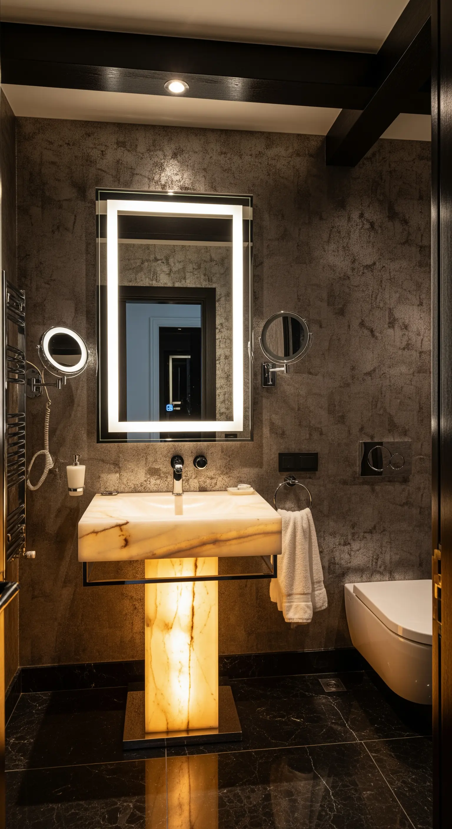 Bagno di lusso con lavabo a colonna in alabastro retroilluminato e pareti scure.