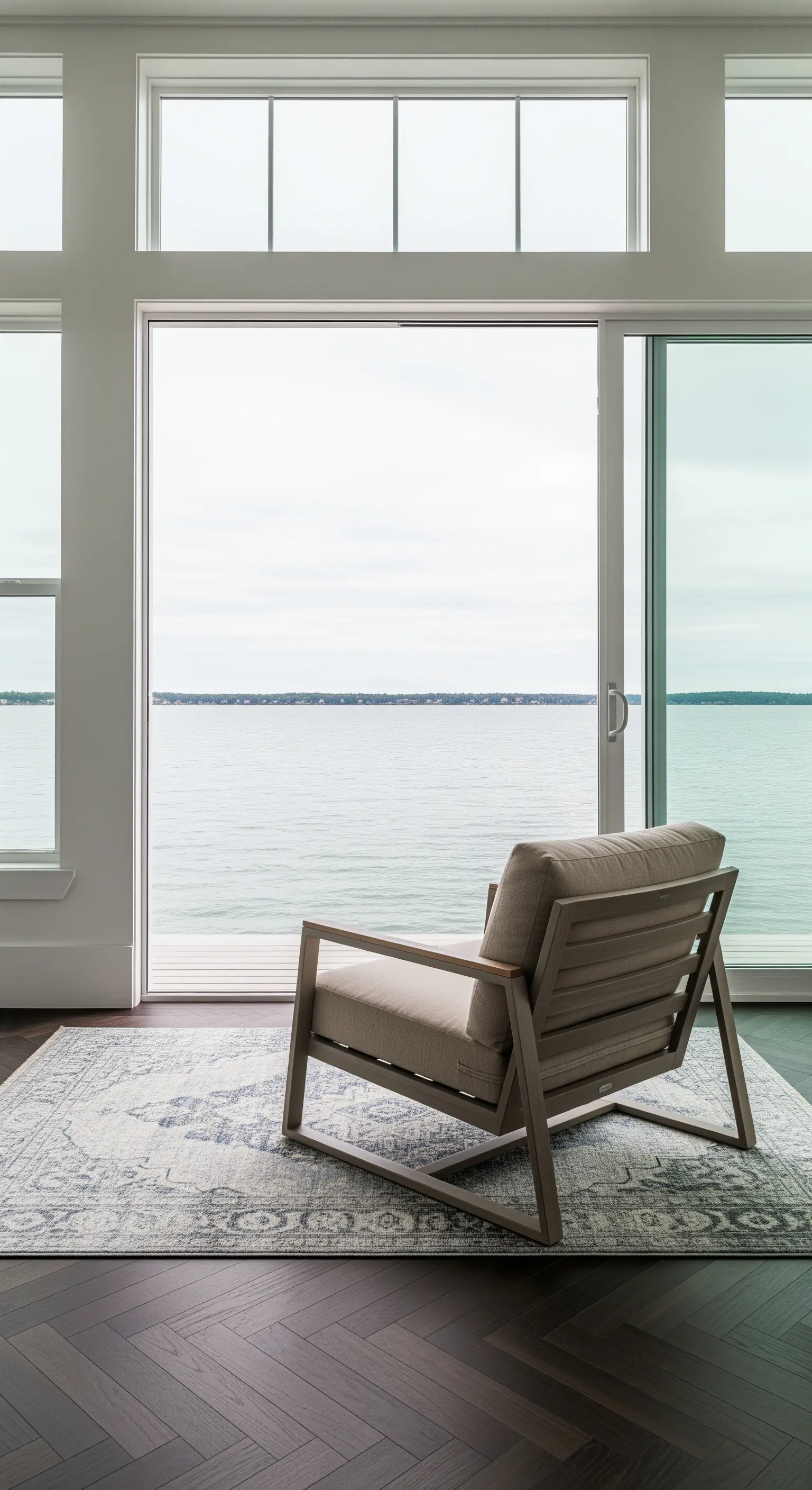 Poltrona minimalista di fronte a una porta-finestra scorrevole con vista sul mare.