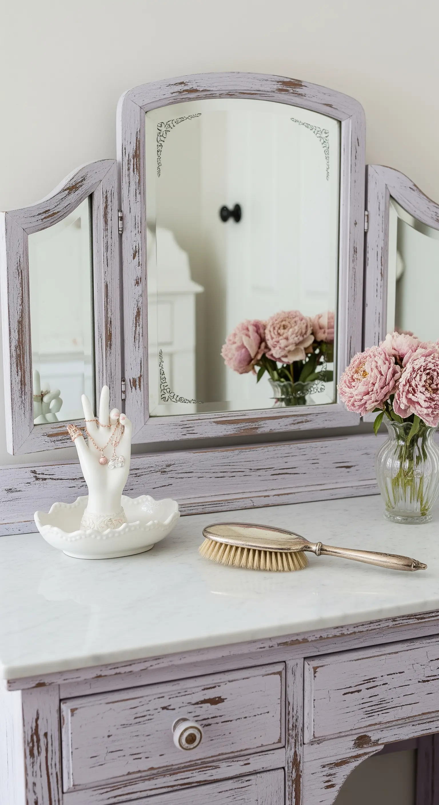 Mobile toeletta color lilla decapé con specchio a tre ante e rose rosa in un vaso.