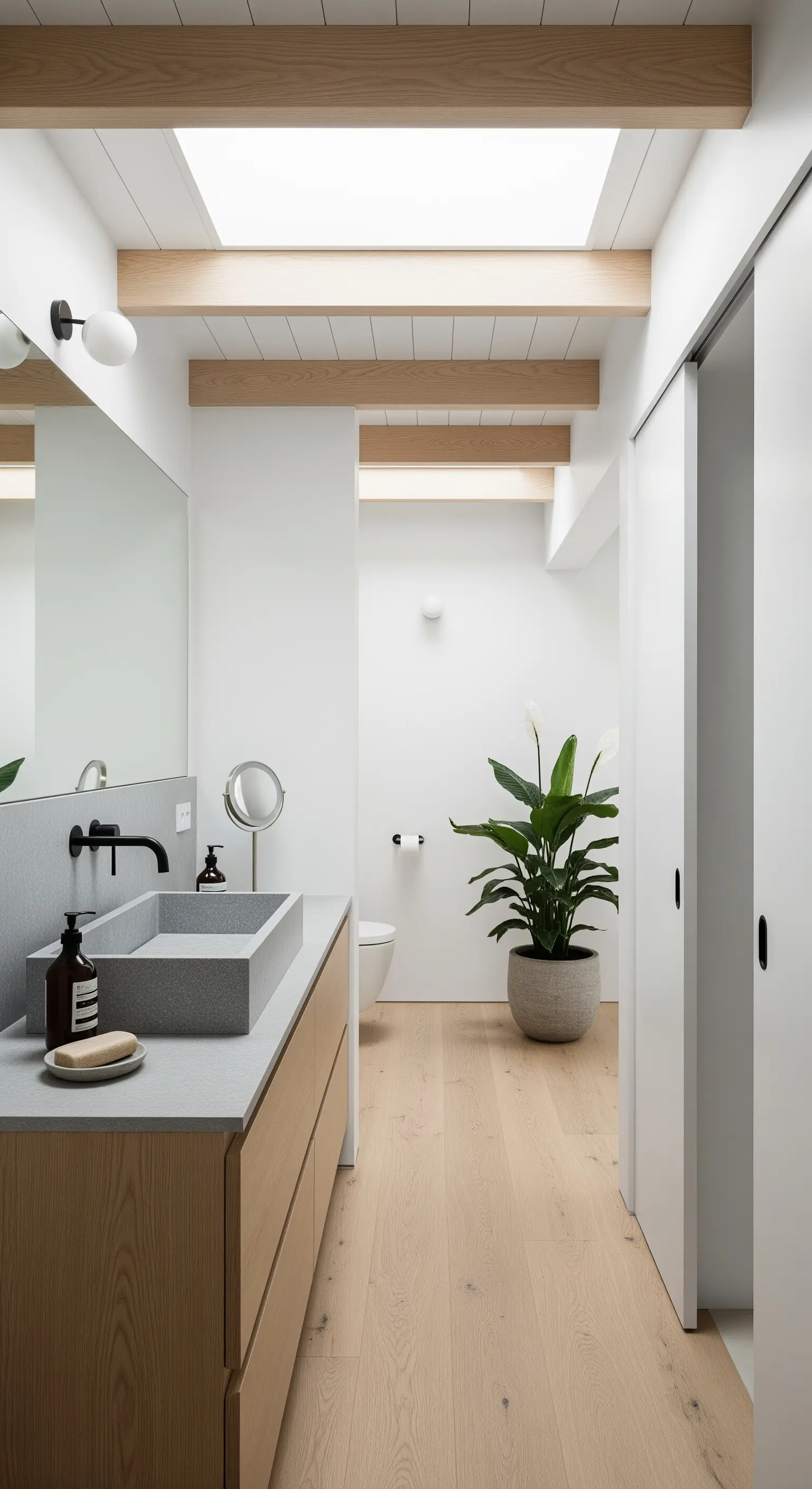 Bagno luminoso con travi in legno chiaro, pareti bianche e lucernario.