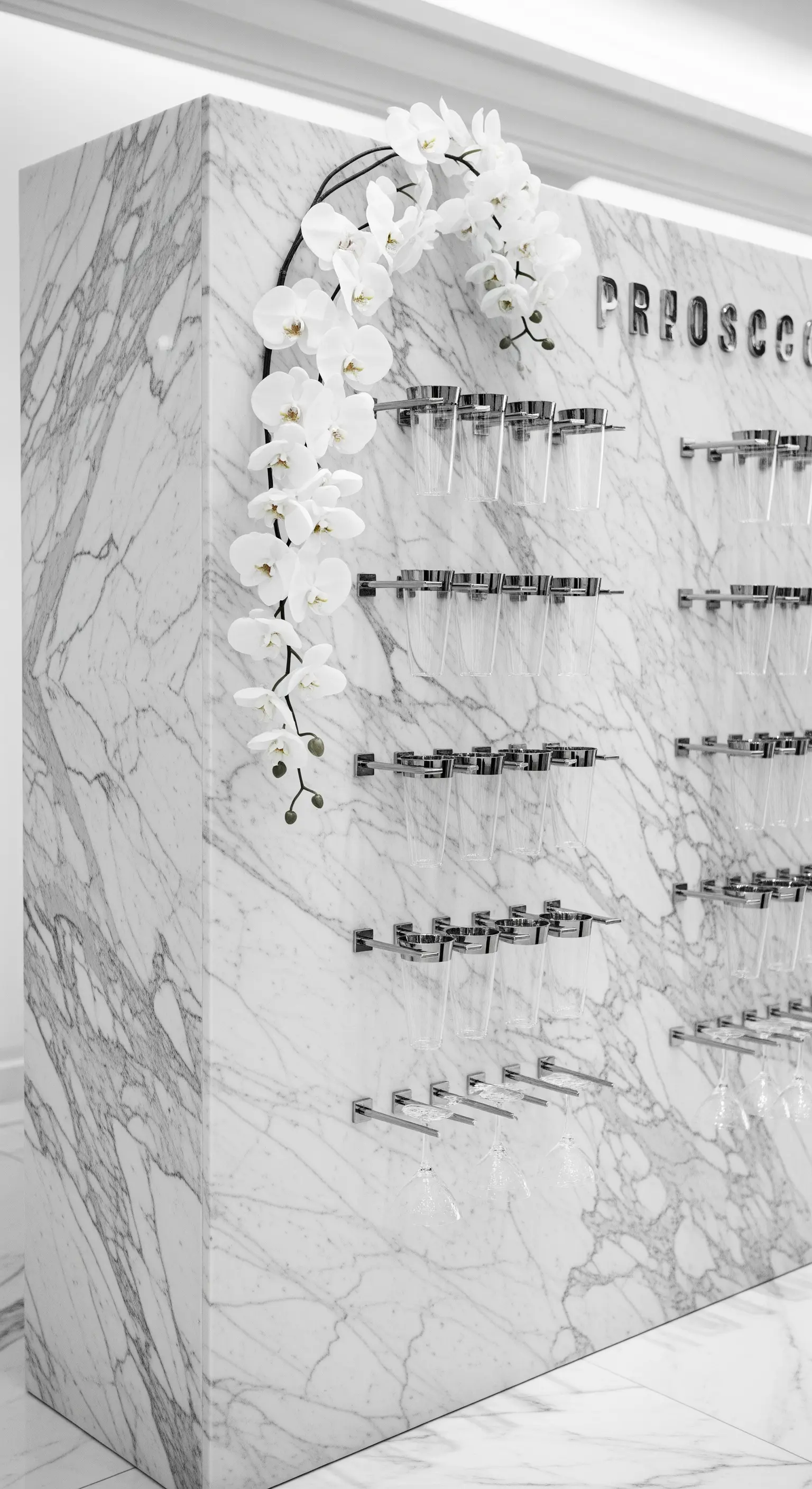 Prosecco wall in marmo bianco con supporti cromati e una cascata di orchidee bianche.