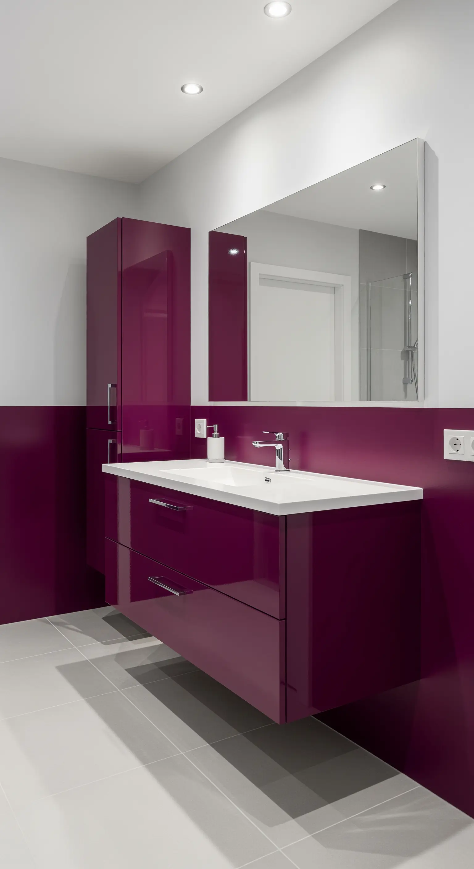 Bagno moderno con pannelli e mobile sospeso laccati in color magenta.