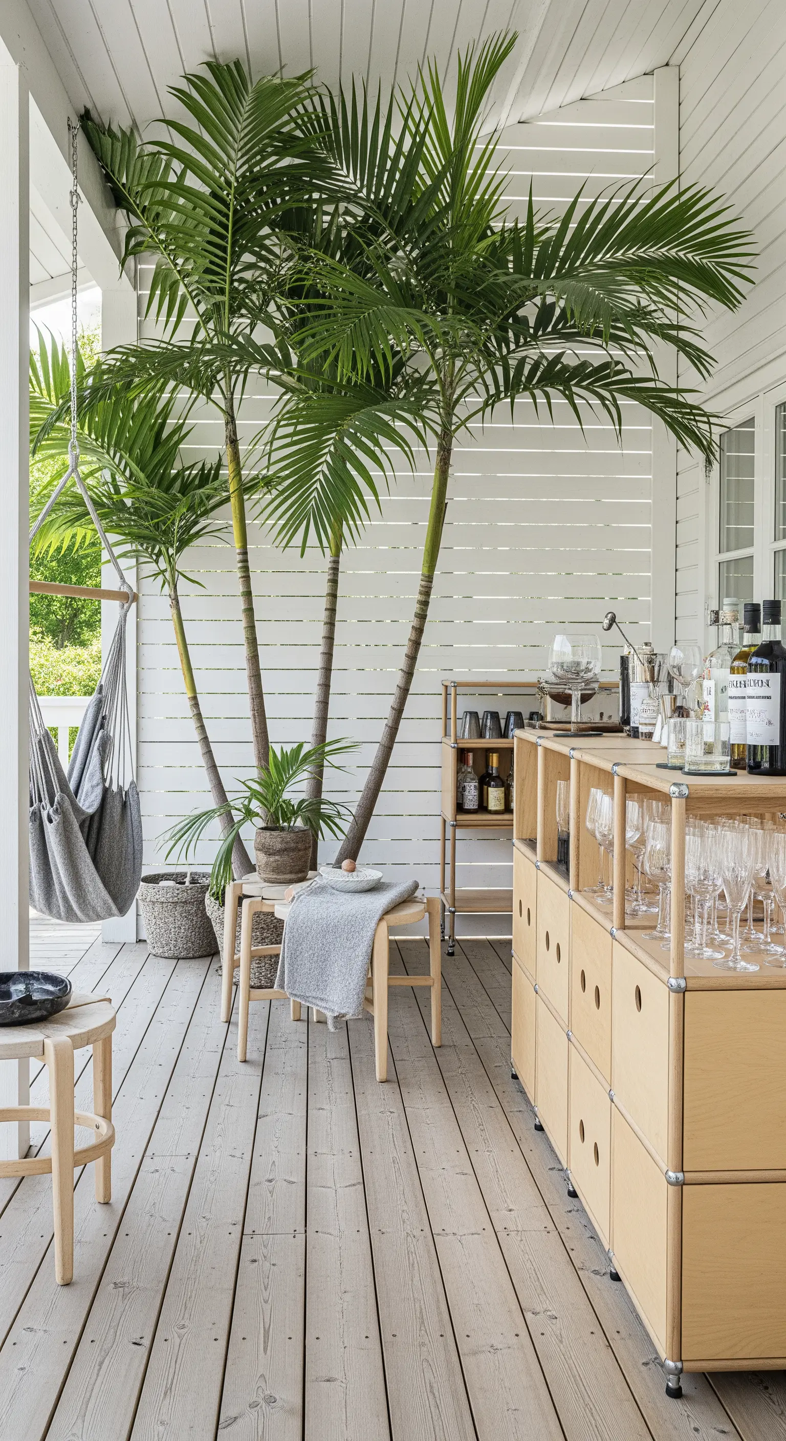 Portico bianco in stile scandinavo con mobili in legno chiaro, palme in vaso e amaca grigia
