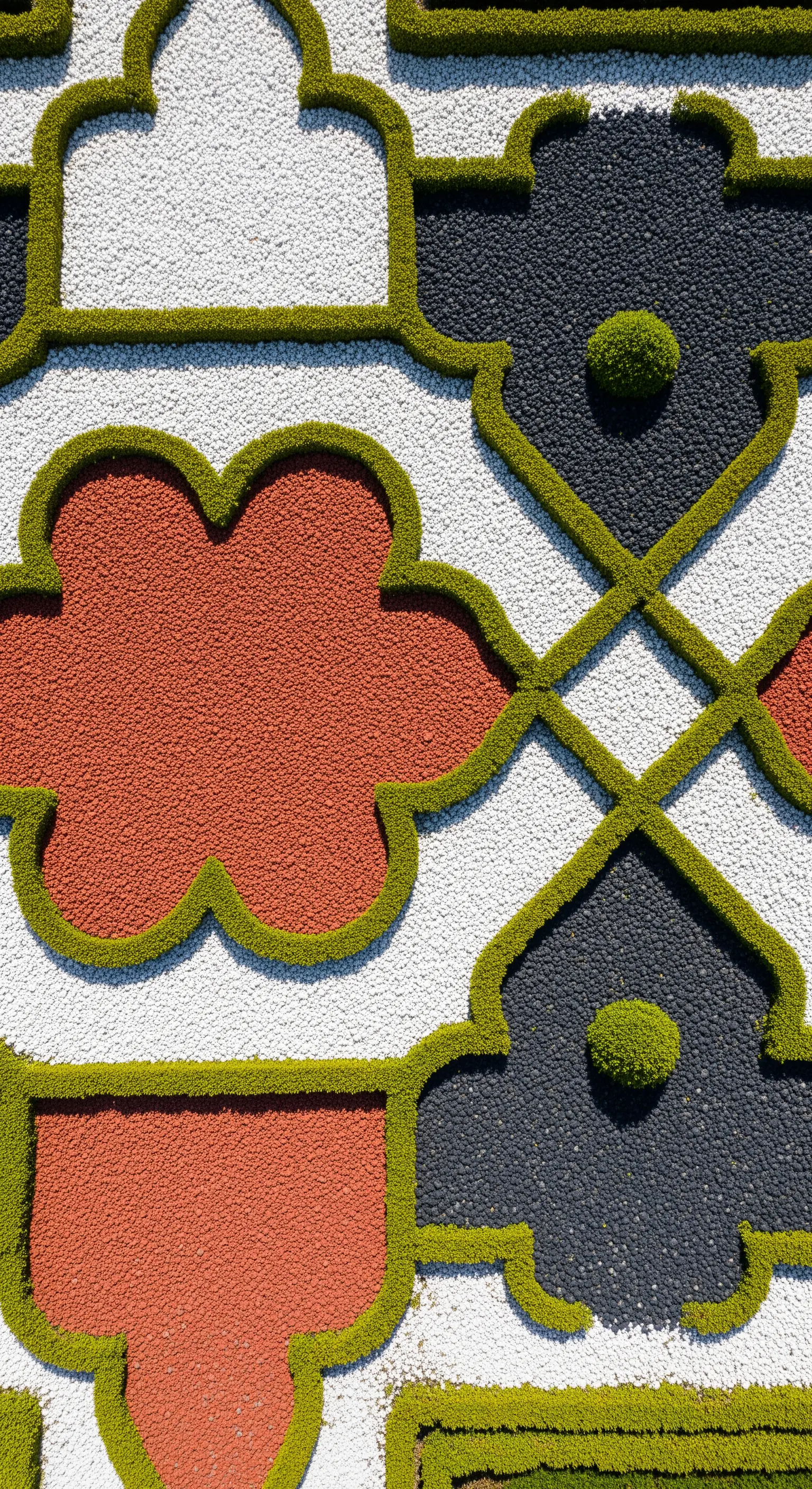 Motivo decorativo a terra creato con ghiaia colorata (bianca, nera, rossa) e bordi di bosso.