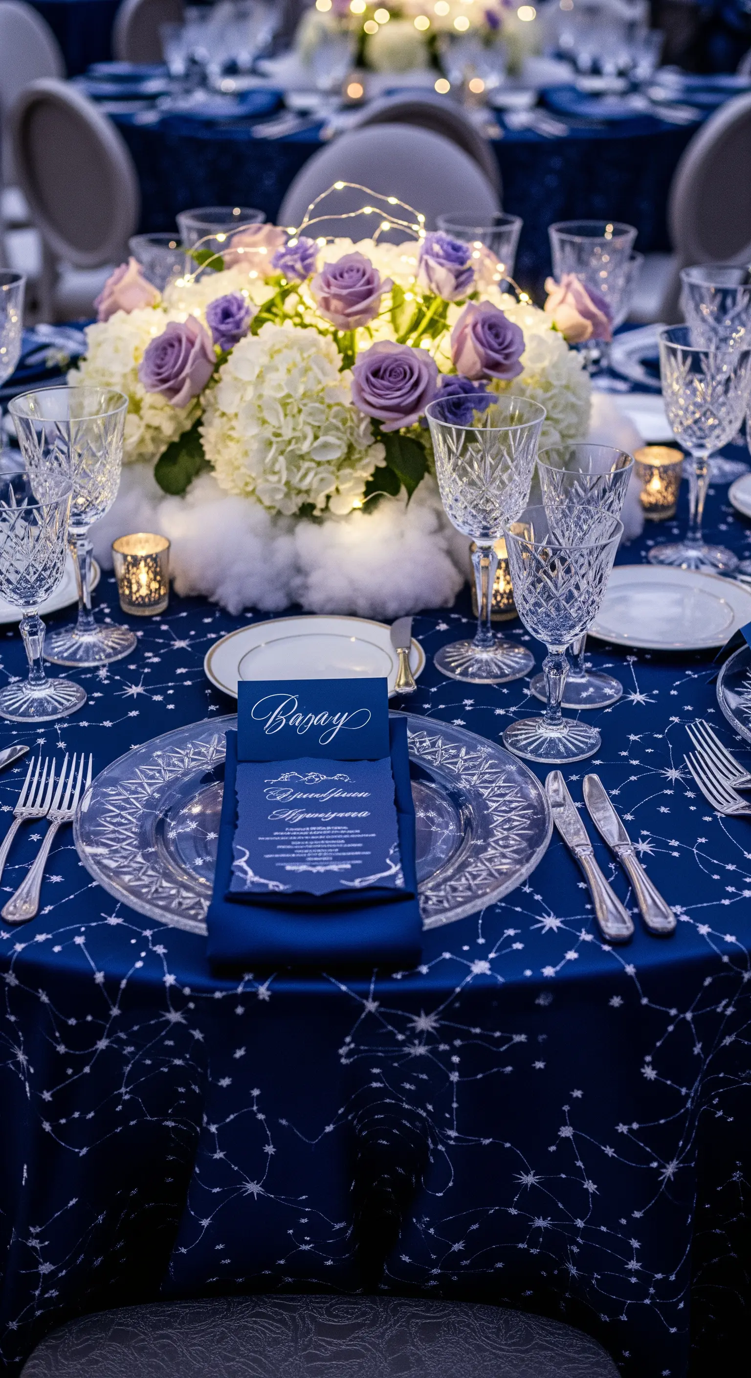 Allestimento a tema celestiale con tovaglia blu stellata e fiori lilla.