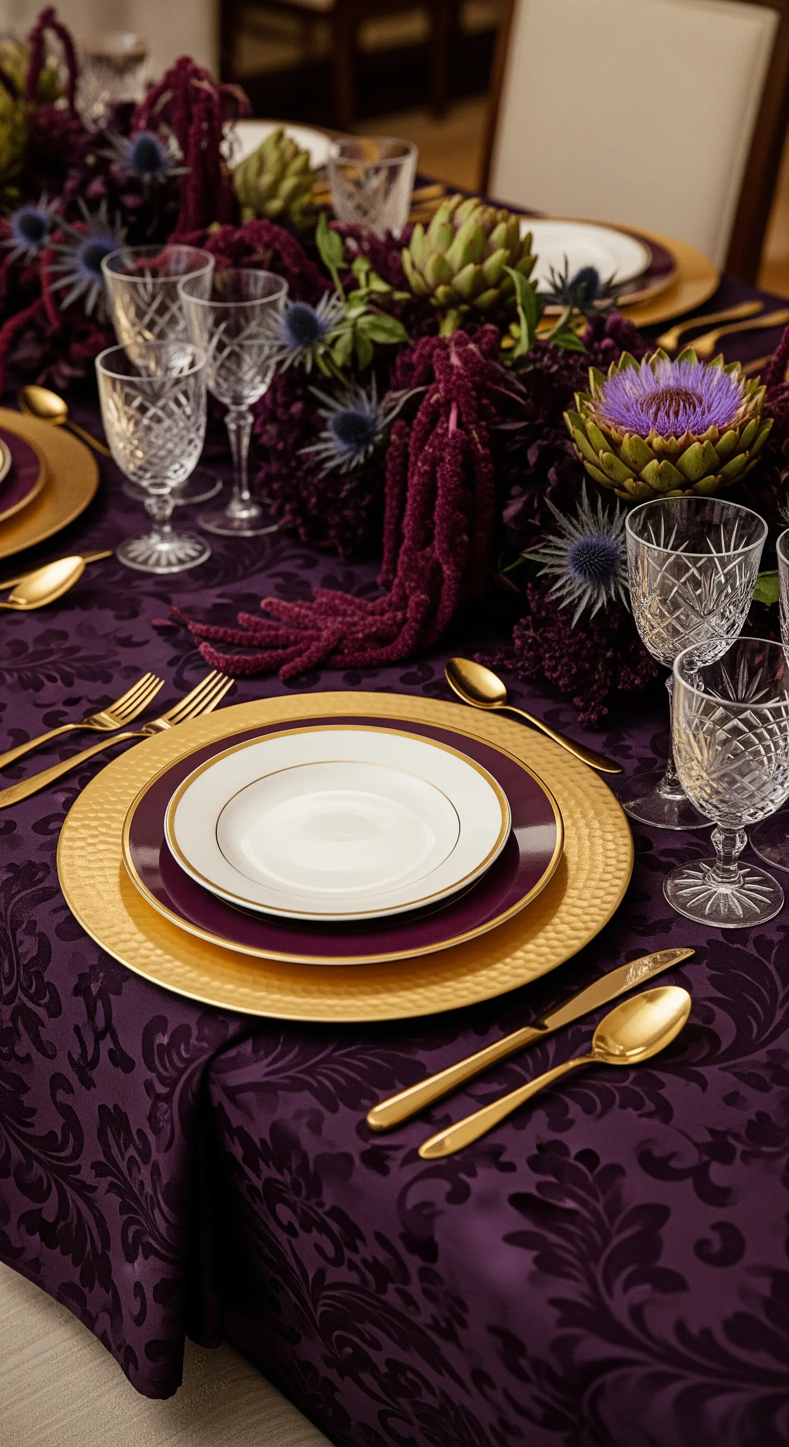 Tavola viola con tovaglia damascata, sottopiatti dorati e centrotavola con carciofi.