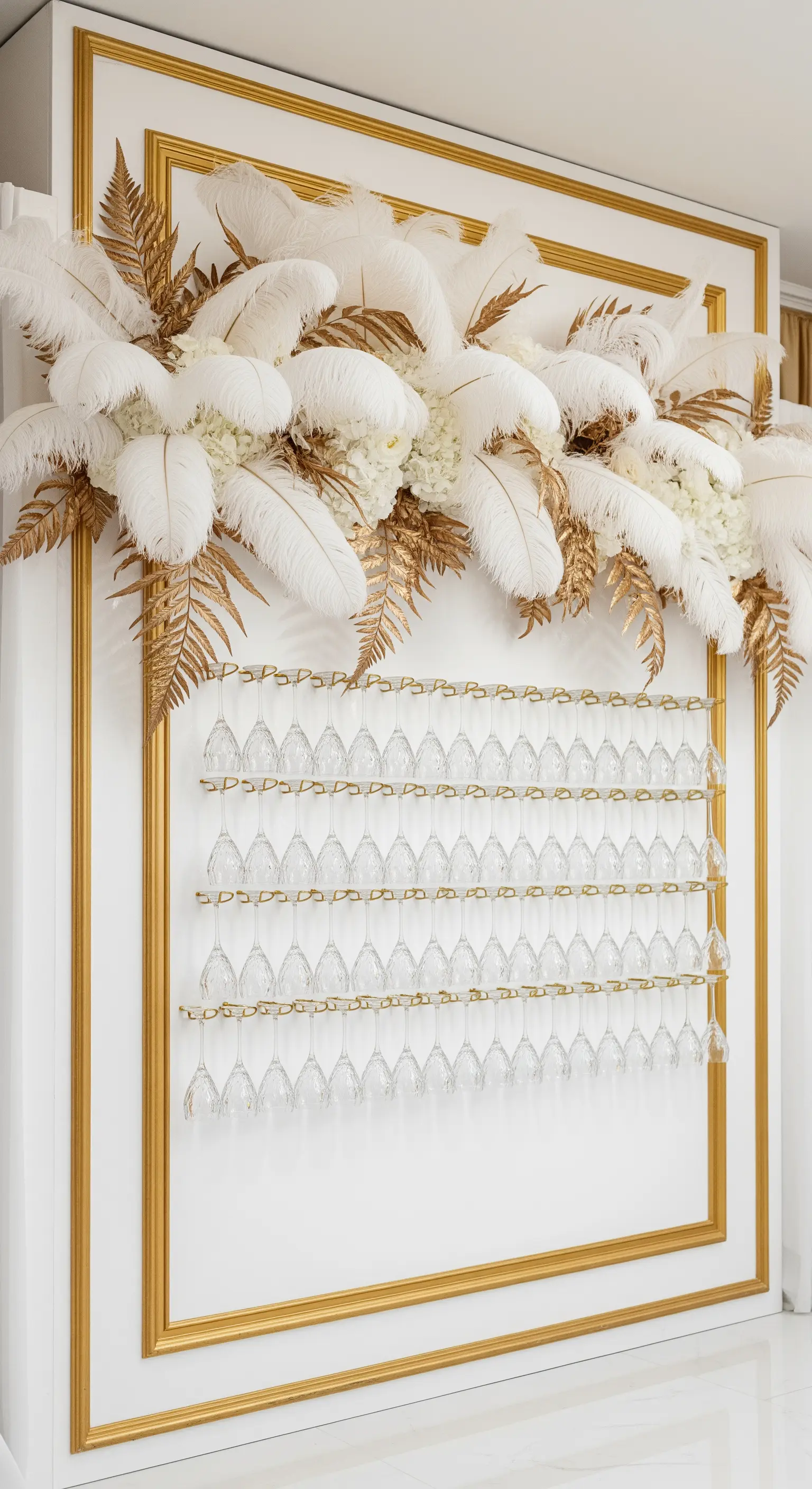 Prosecco wall bianco e oro con una composizione di piume bianche e felci dorate.