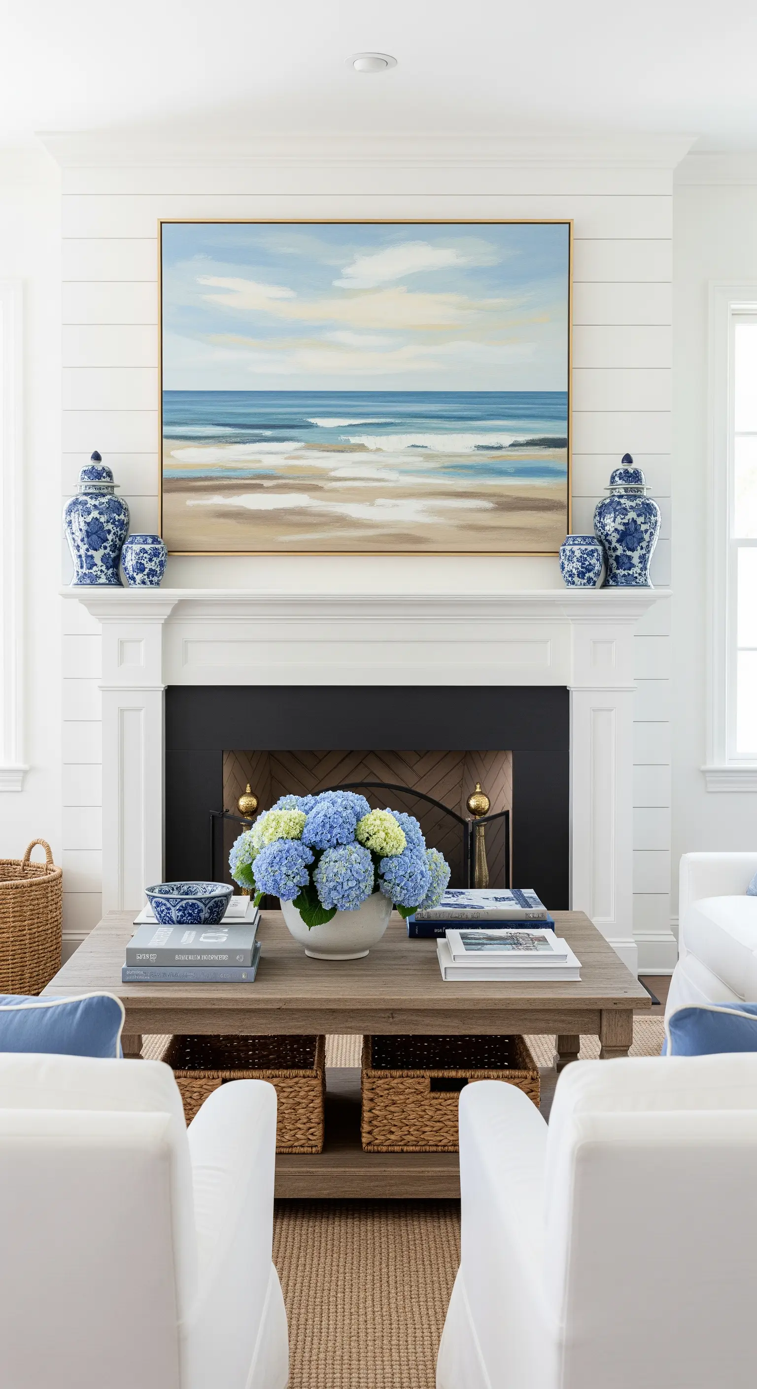 Quadro di un paesaggio marino astratto sopra un camino bianco in un soggiorno in stile costiero.