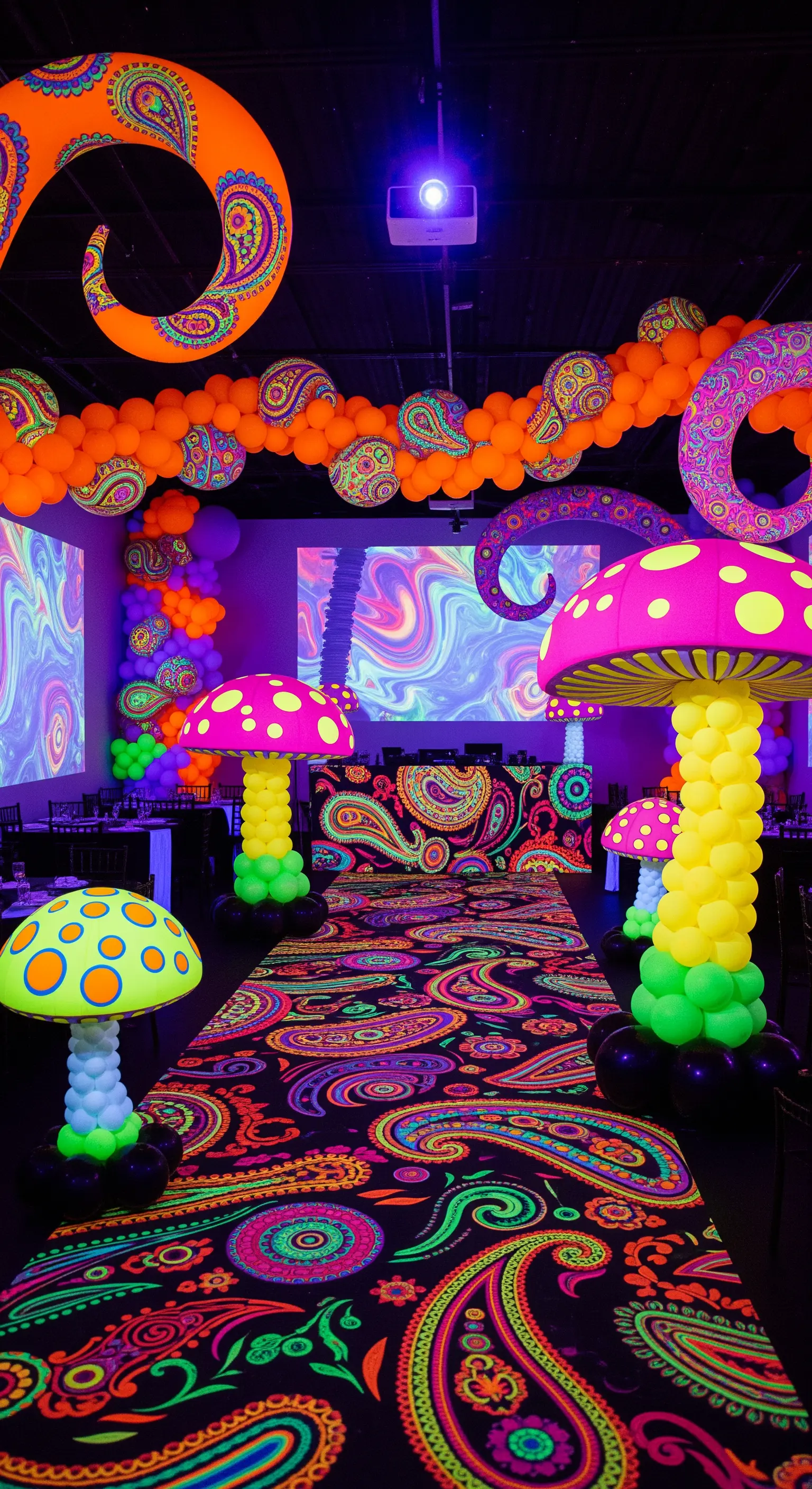 Allestimento psichedelico con tappeto Paisley fluorescente e funghi giganti fatti di palloncini.
