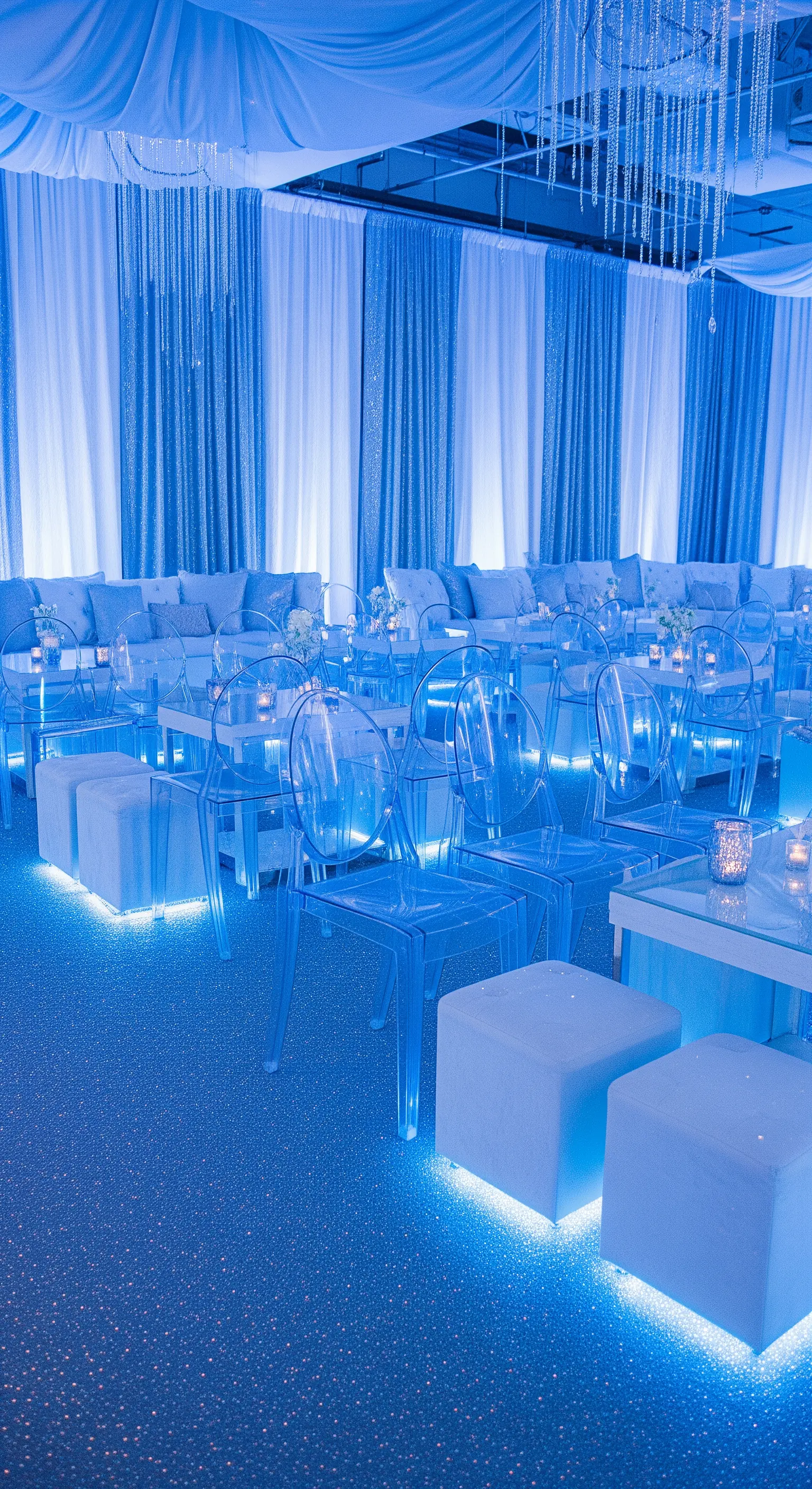 Allestimento per feste con luci blu, sedie trasparenti e cubi luminosi come sedute.