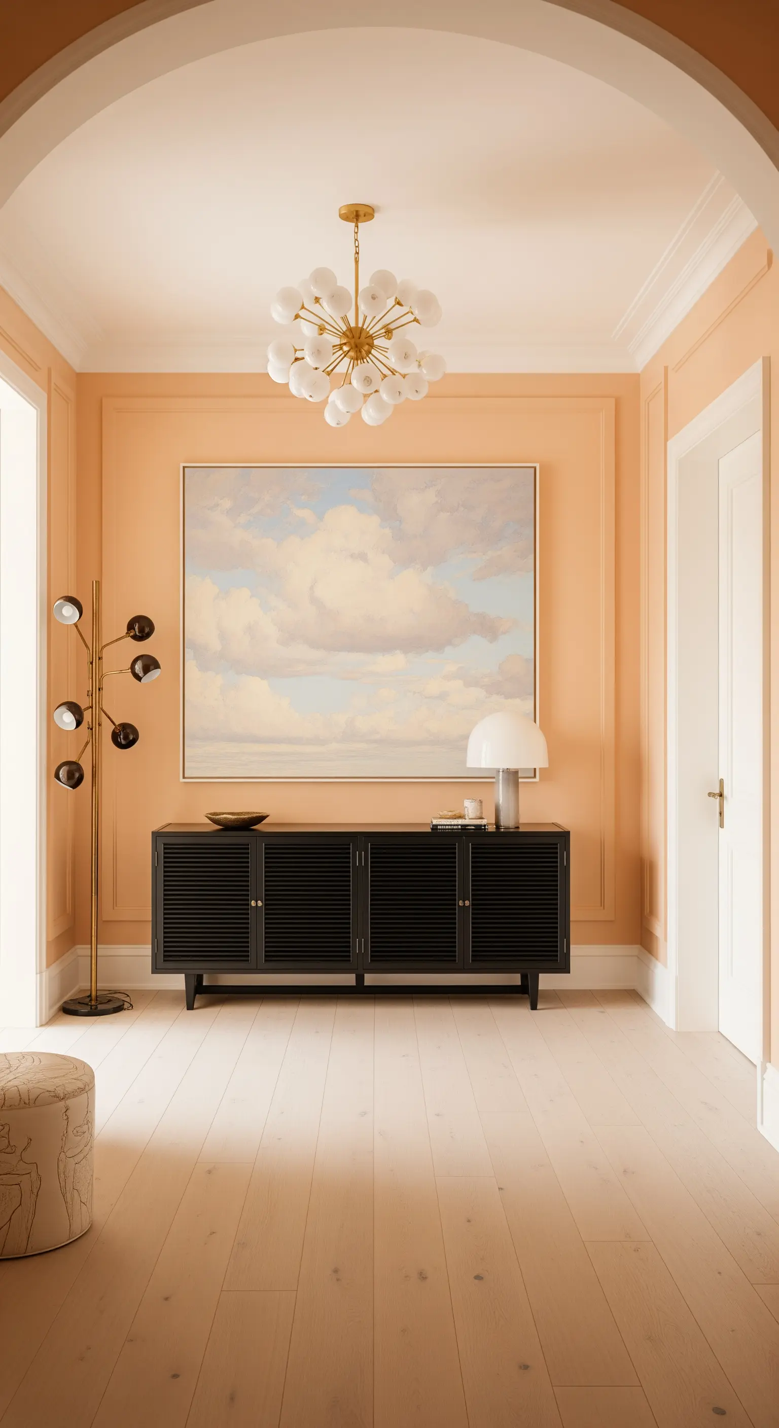 Parete color pesca con credenza nera e un grande quadro con nuvole.