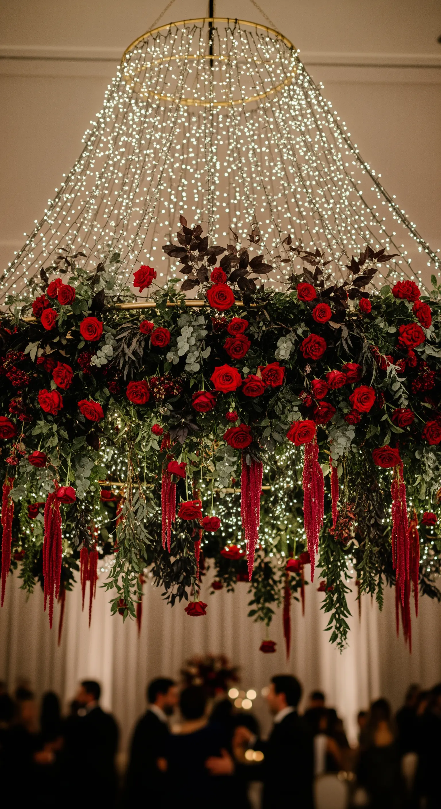 Grande installazione floreale sospesa con rose rosse e una cascata di lucine a LED.