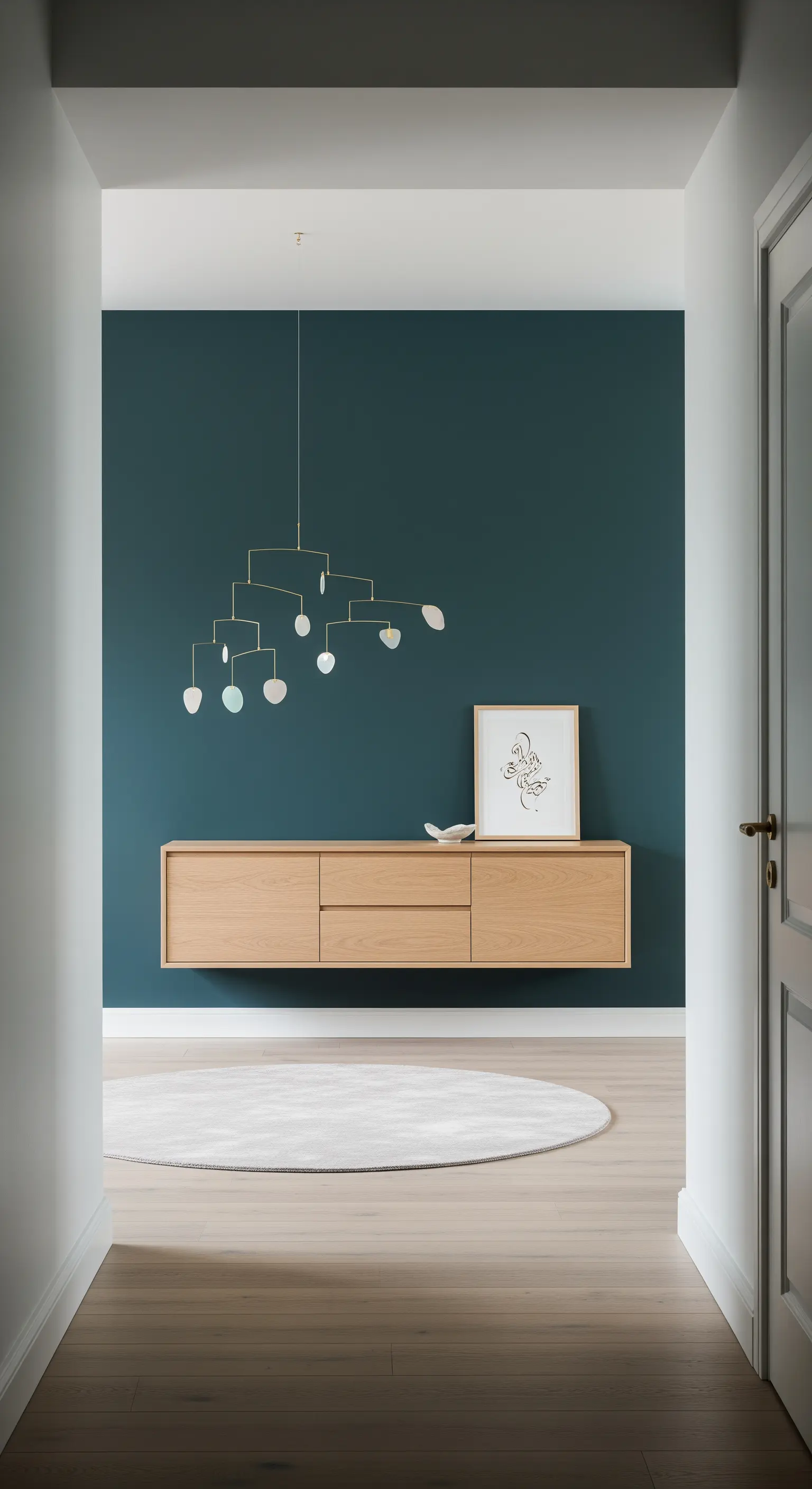 Parete di fondo blu petrolio con consolle sospesa in rovere e scultura mobile dorata.