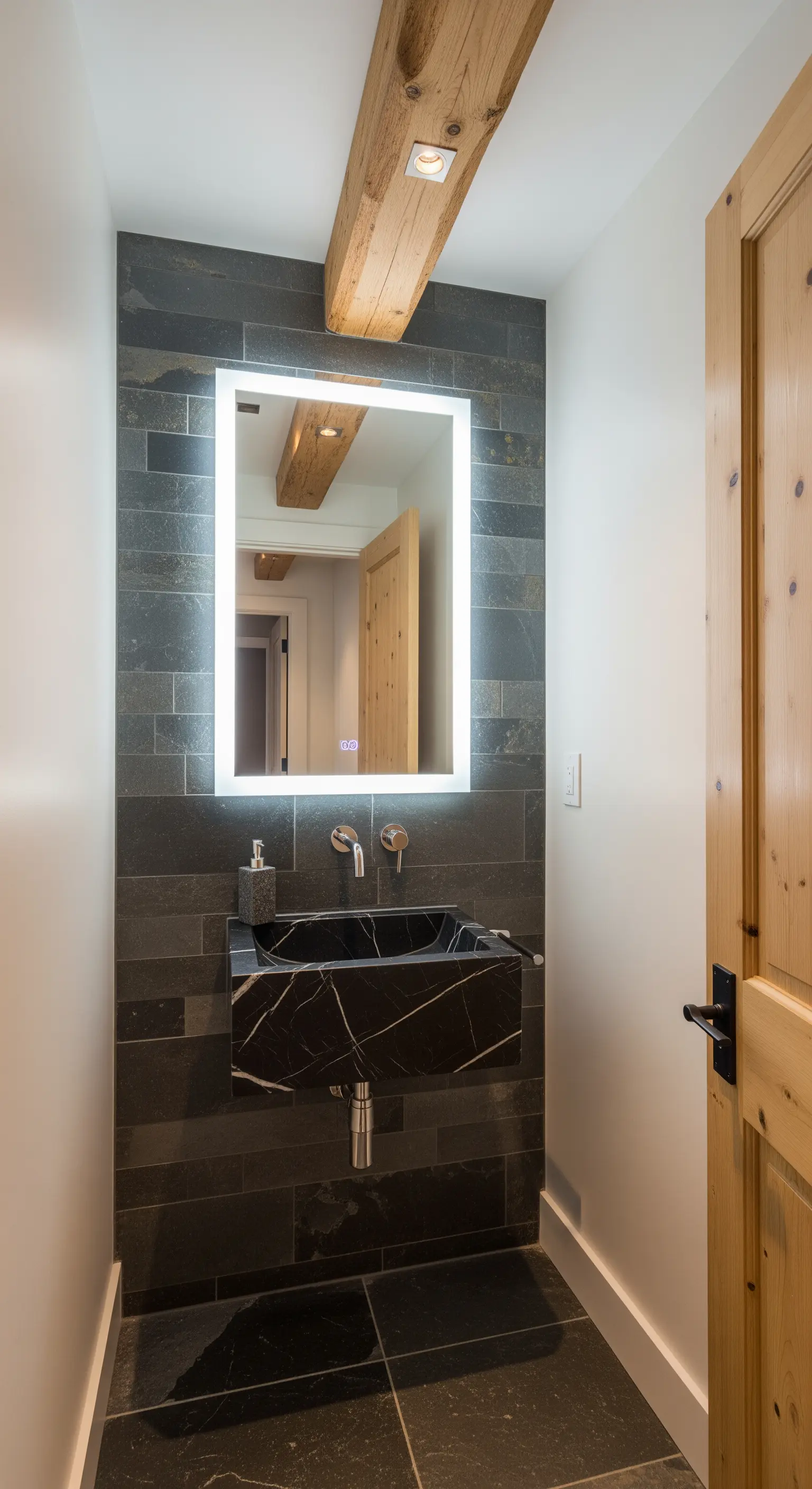Bagno piccolo con parete in ardesia, specchio retroilluminato e lavabo in marmo nero.