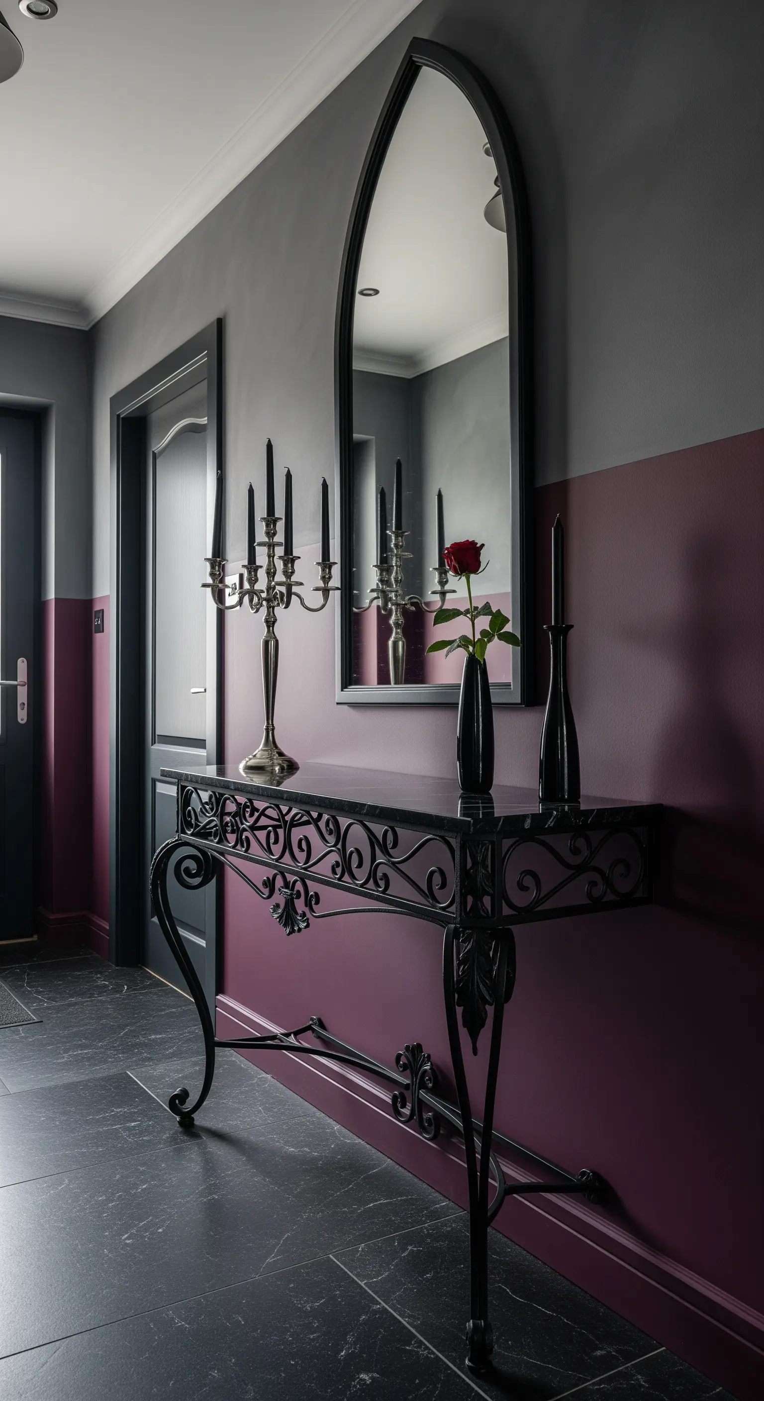 Ingresso in stile gotico con parete prugna e grigia, e consolle in ferro battuto.
