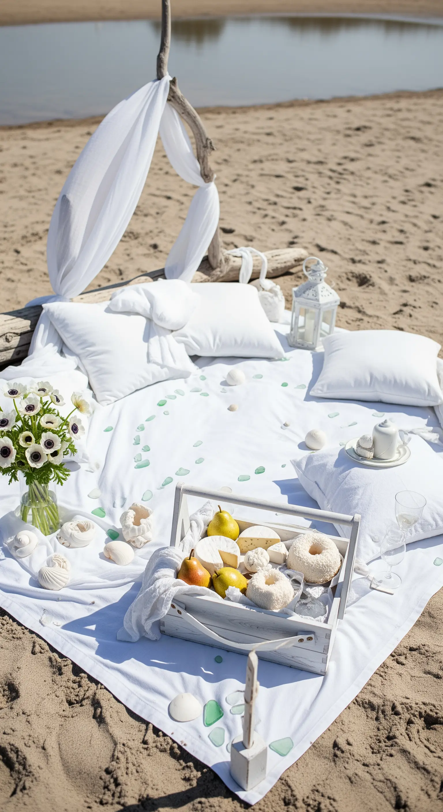 Picnic total white sulla spiaggia con teli di lino, cuscini e una tenda improvvisata.